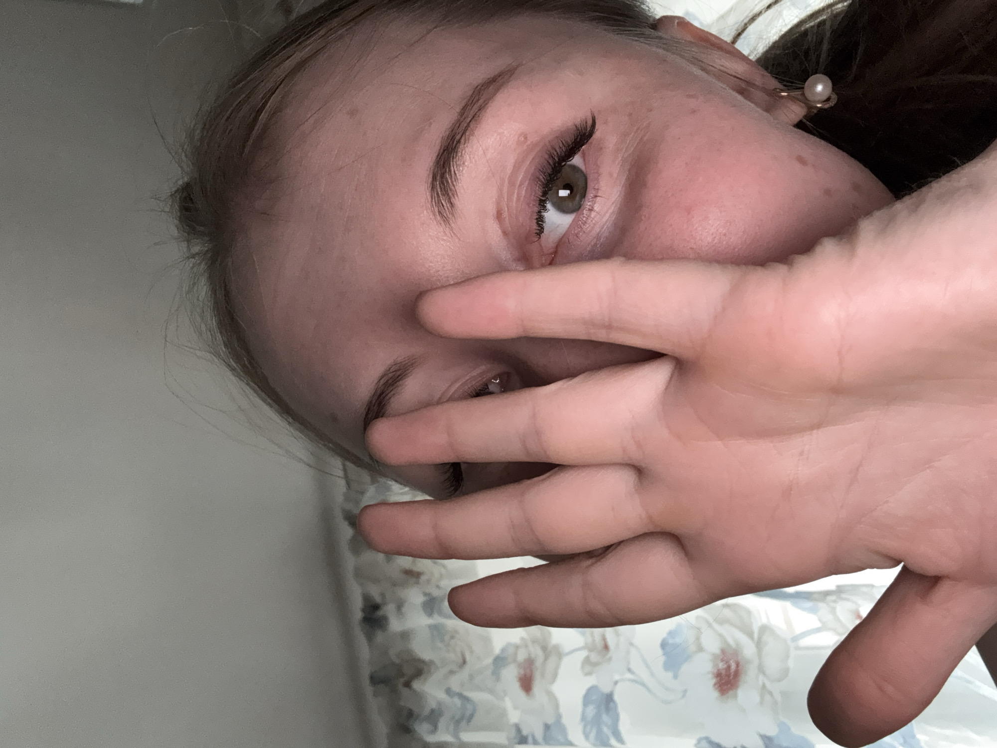 Person captured in angled portrait covering face with hand