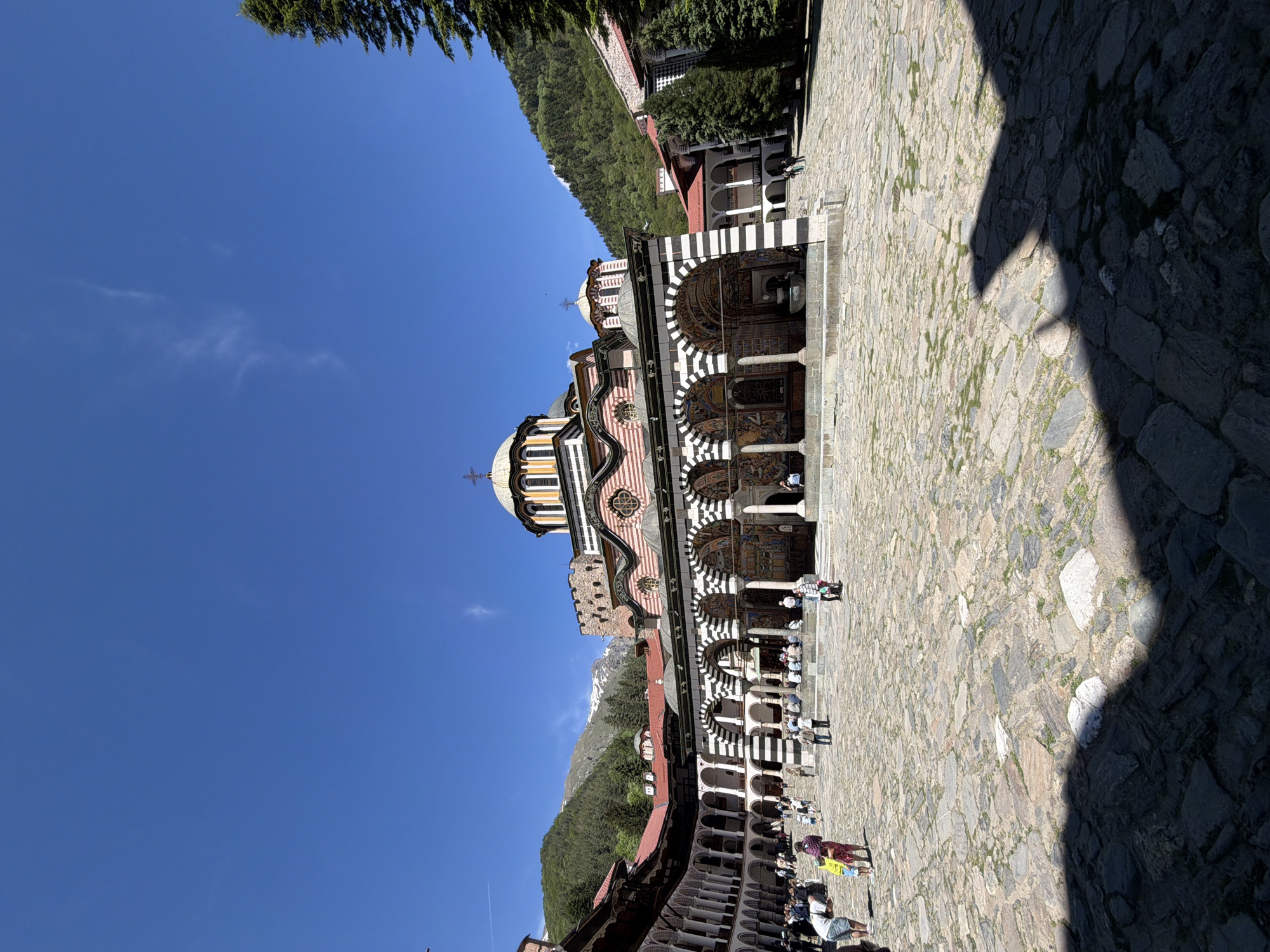 Tourist captures Rila Monastery's striped architecture during sunny visit