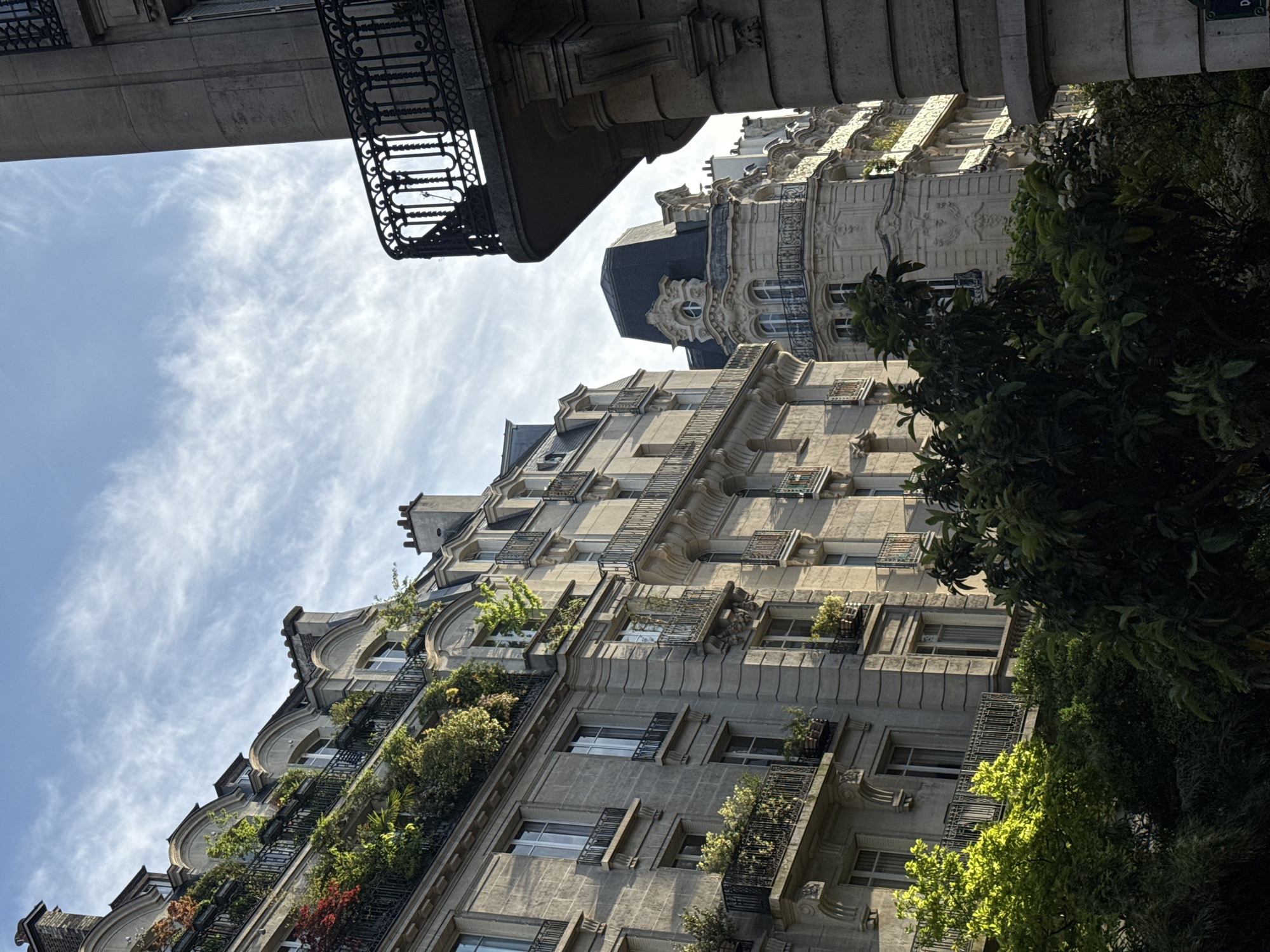 Parisian apartment buildings observed under partly cloudy afternoon sky