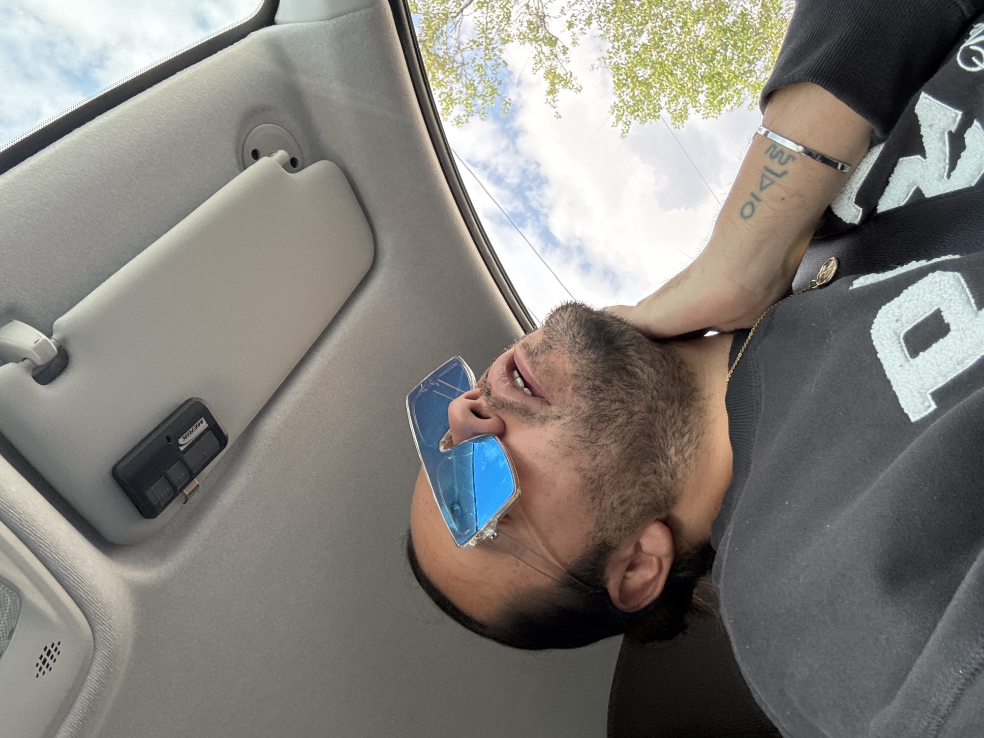 Man in blue sunglasses gazes skyward from car interior