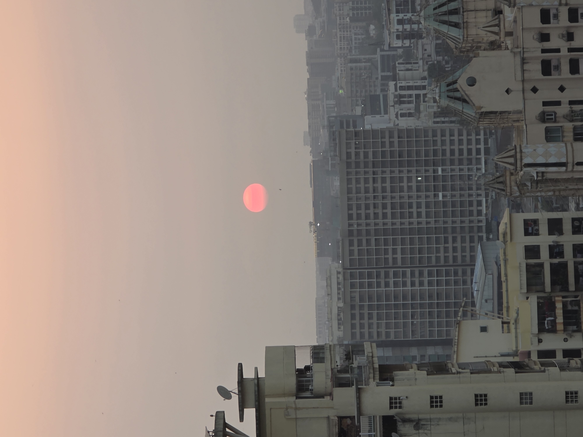 Vivid red-orange sun captured over Mumbai's hazy skyline