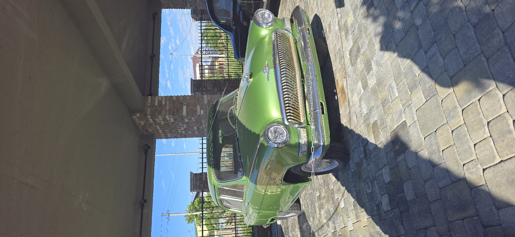 Classic car gathering observed near deteriorating brick building