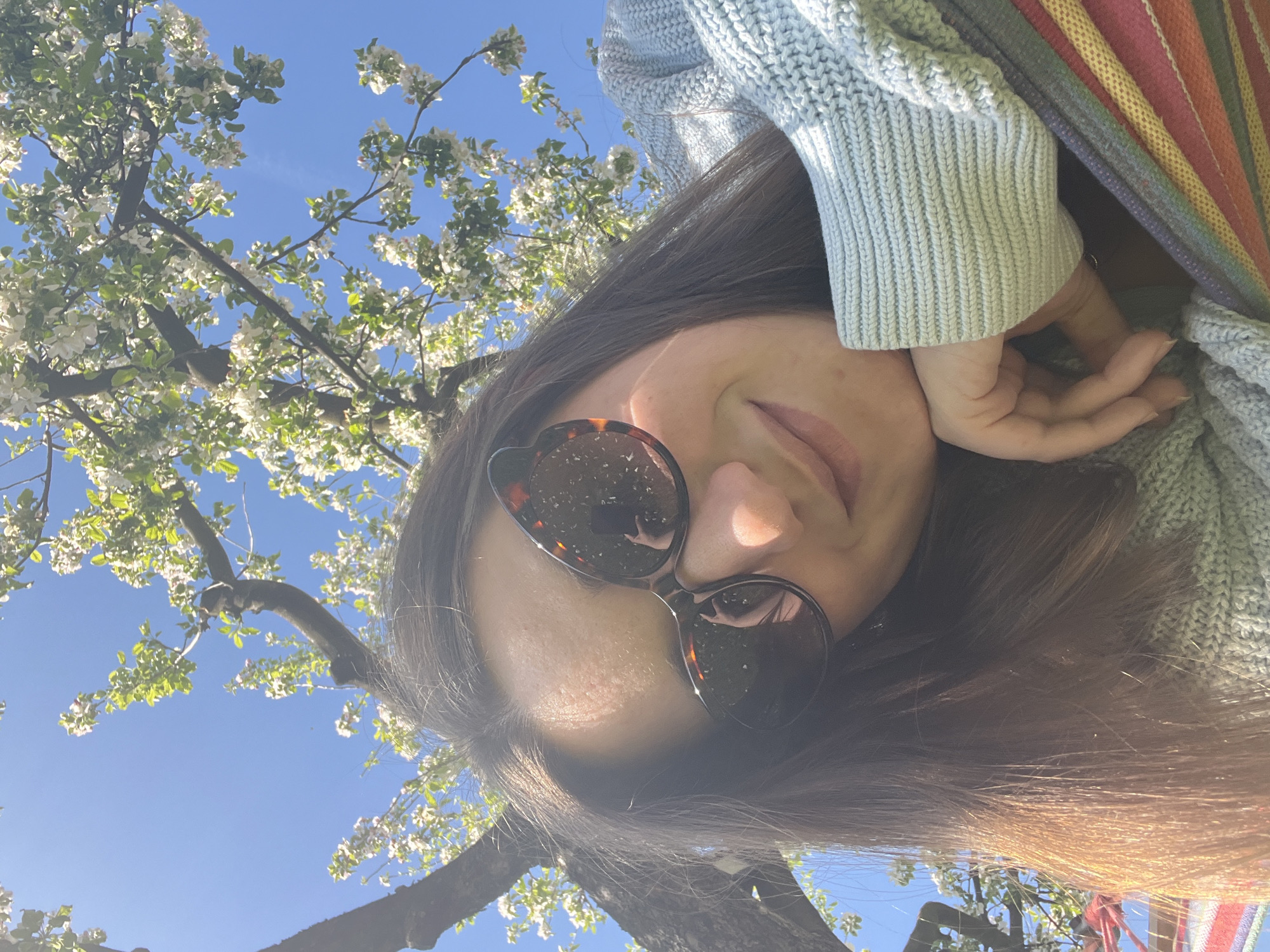 Woman photographs outdoor spring scene with dog, flowering trees