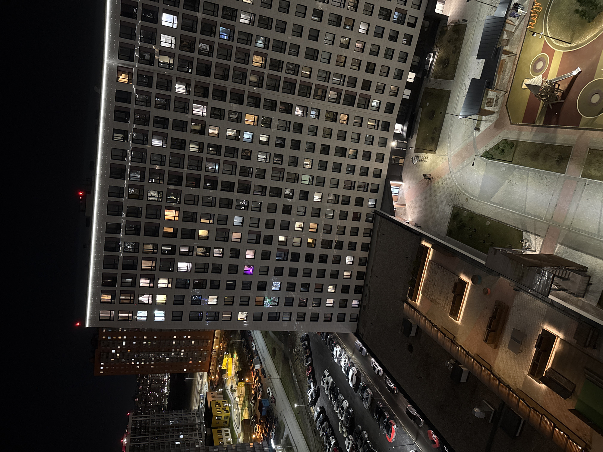 Nighttime aerial view captures illuminated residential building in Murino