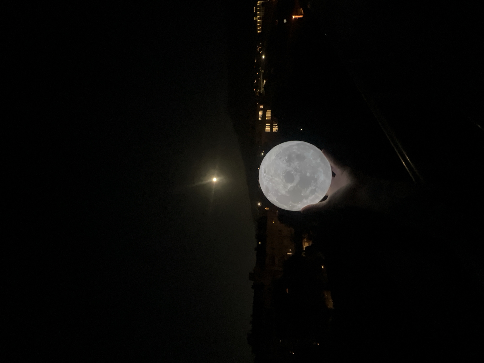 Person holds moon lamp beneath real moon in Sofia