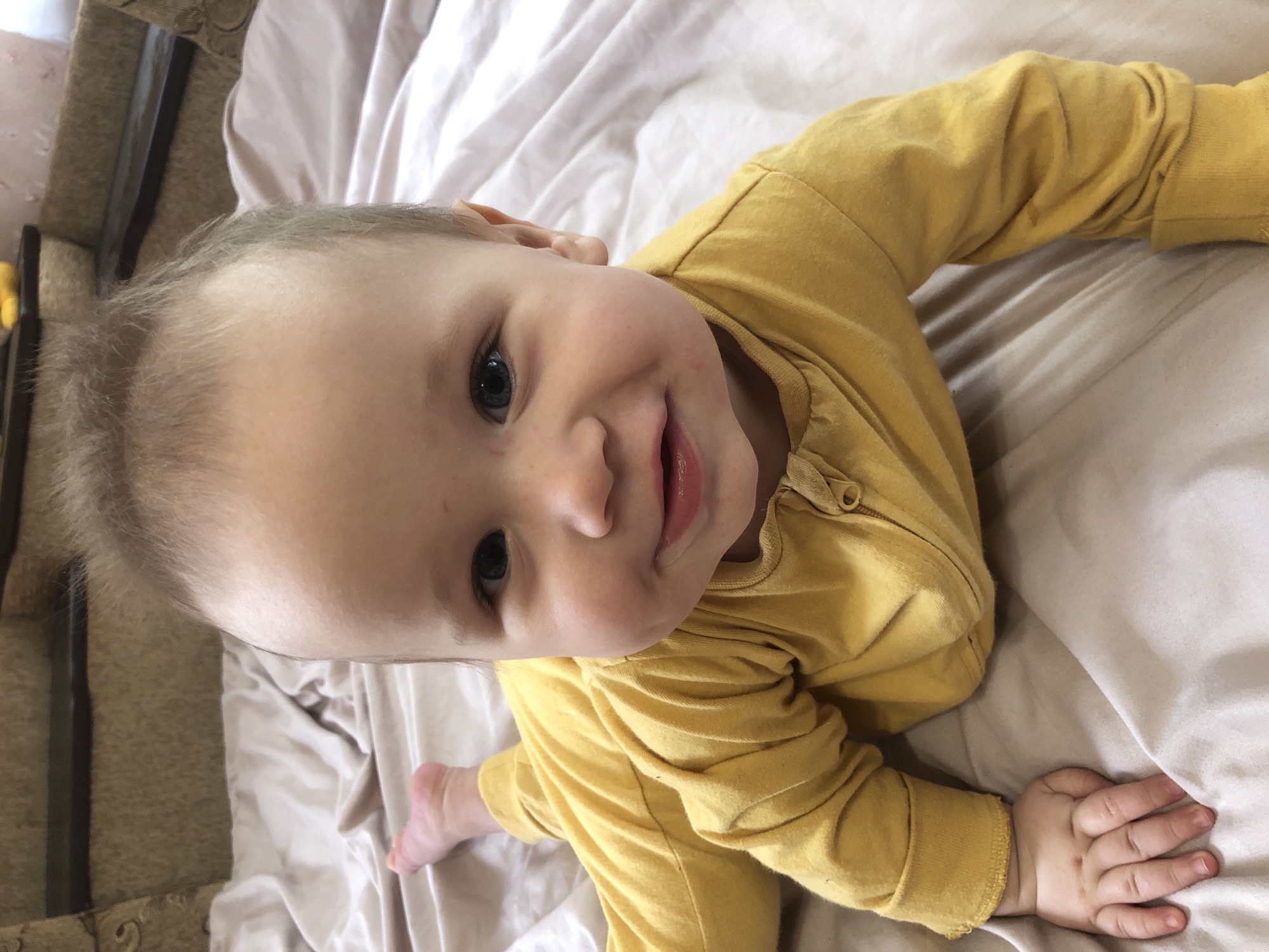 Baby in yellow pajamas resting on a comforter in Radomyshl