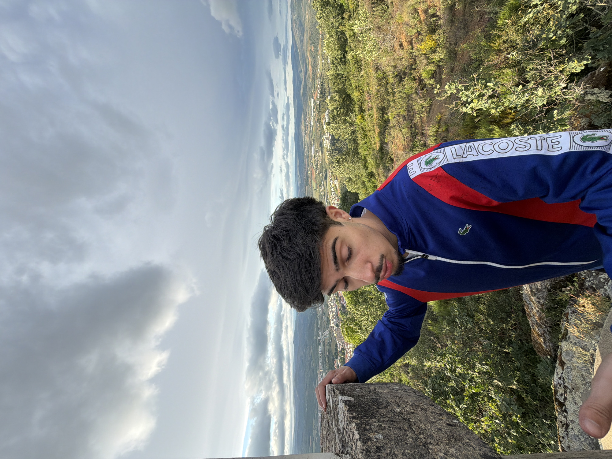 Man in Lacoste jacket overlooks Bragança from stone wall