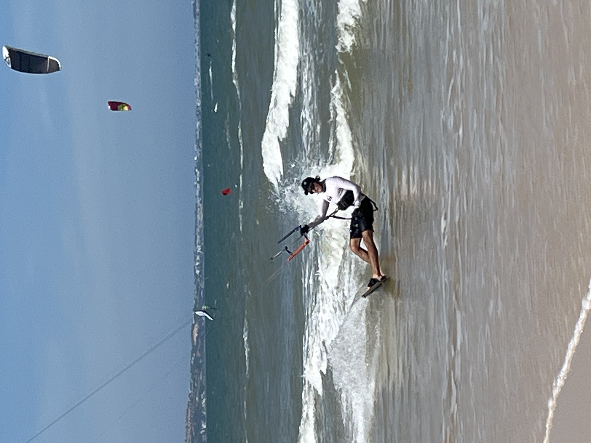Kiteboarding off a sunny Vietnamese coastline on a choppy morning