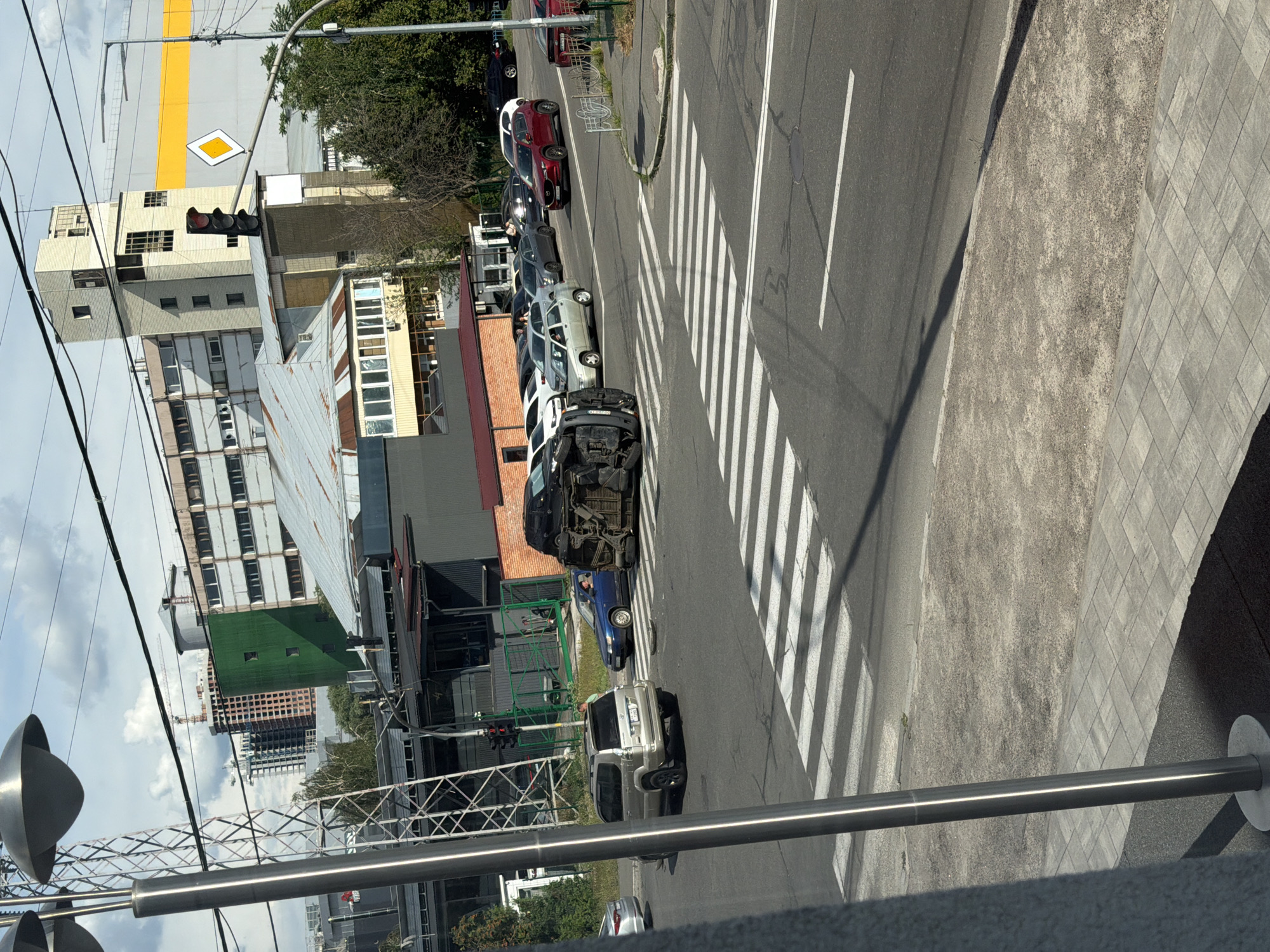 Black car flipped on its side at urban pedestrian crossing