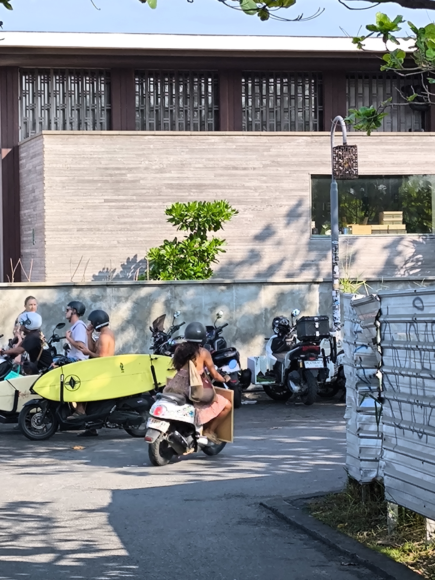 Woman rides white scooter through Canggu street scene