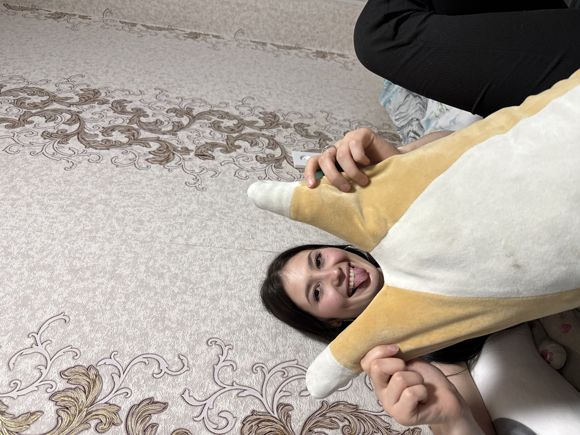 Woman plays with corgi pillow on bed in Russia
