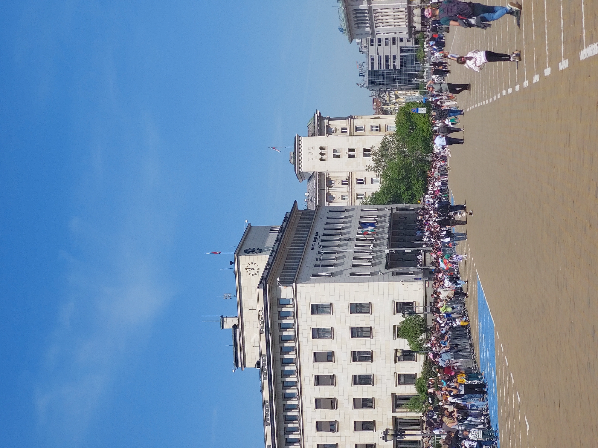 Crowd gathers behind fence near urban clock tower building