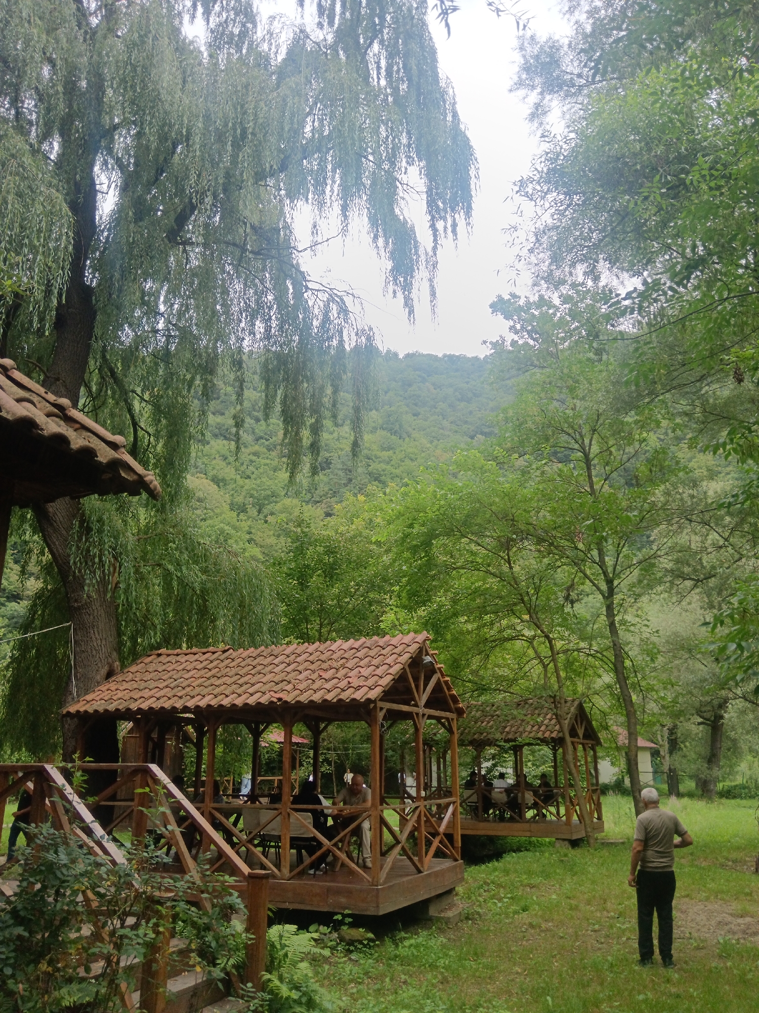 Murky river and wooden pavilions in a green riverside park