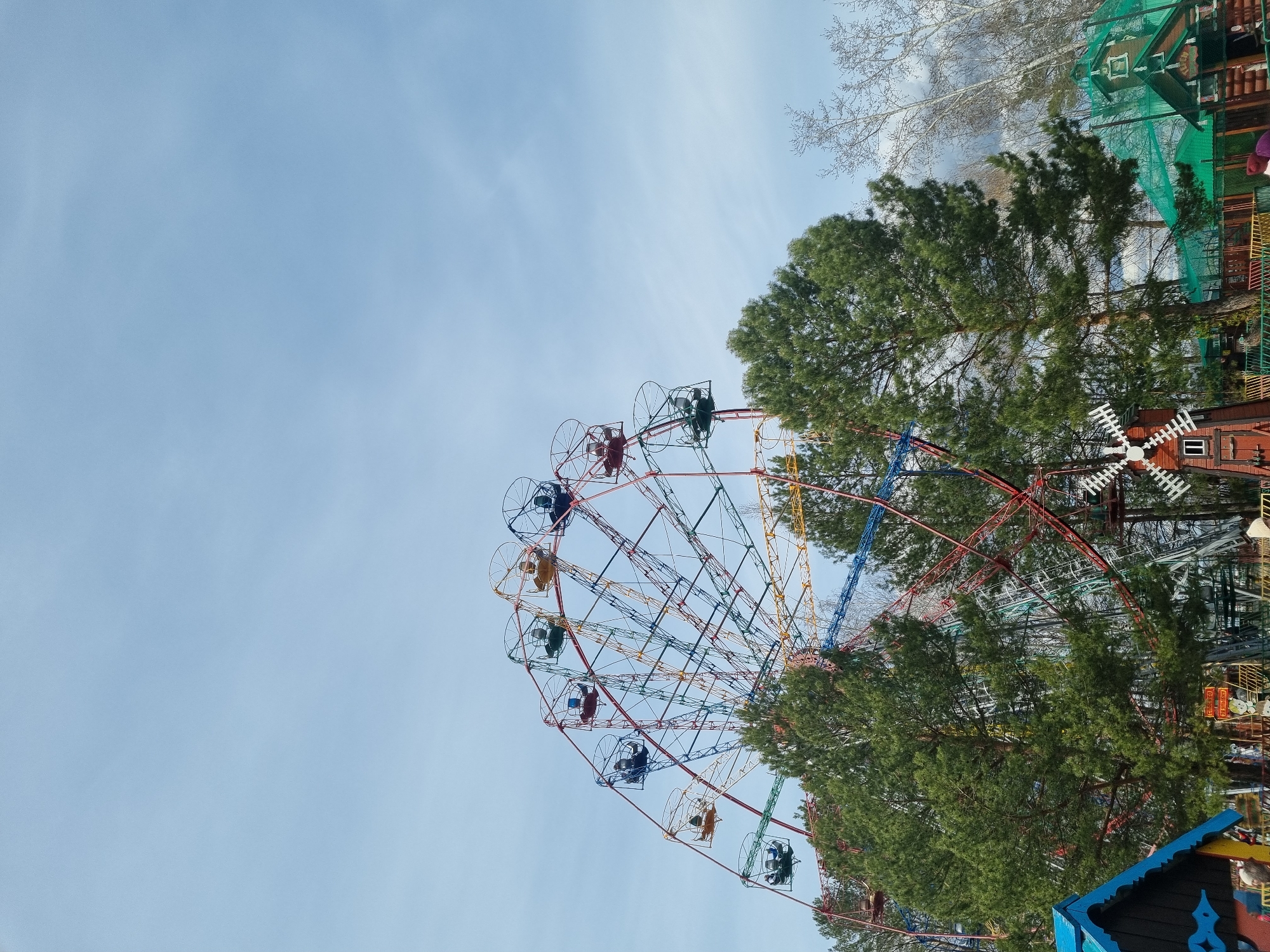 Children explore padlock fence near Ferris wheel on sunny morning