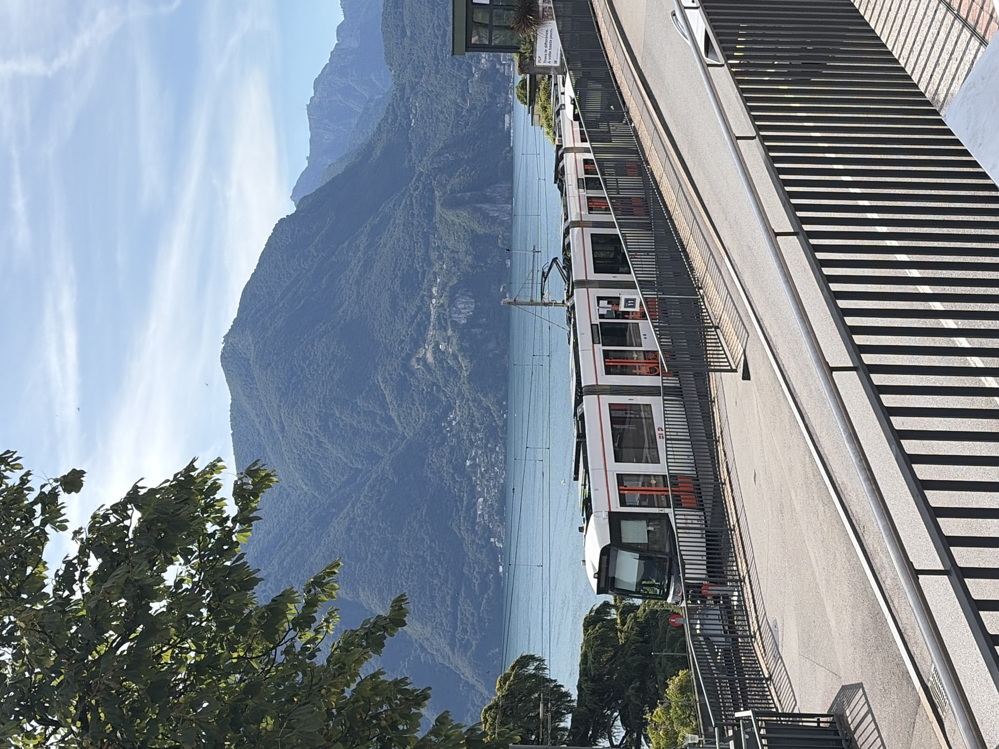 Lugano lakefront, trams, trains, and mountain views on a summer morning