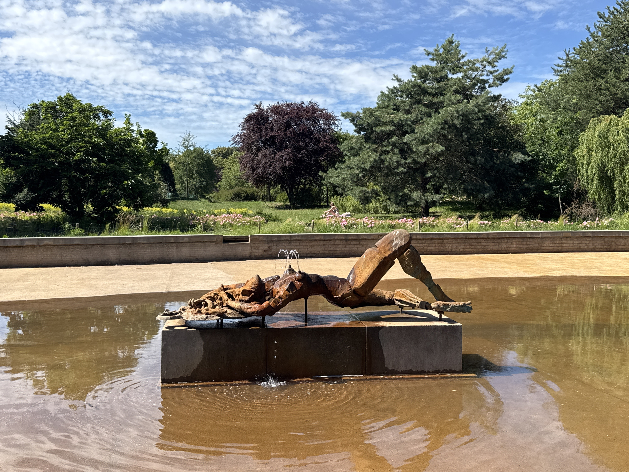 Bronze fountain sculpture and a dog cooling off in Warsaw