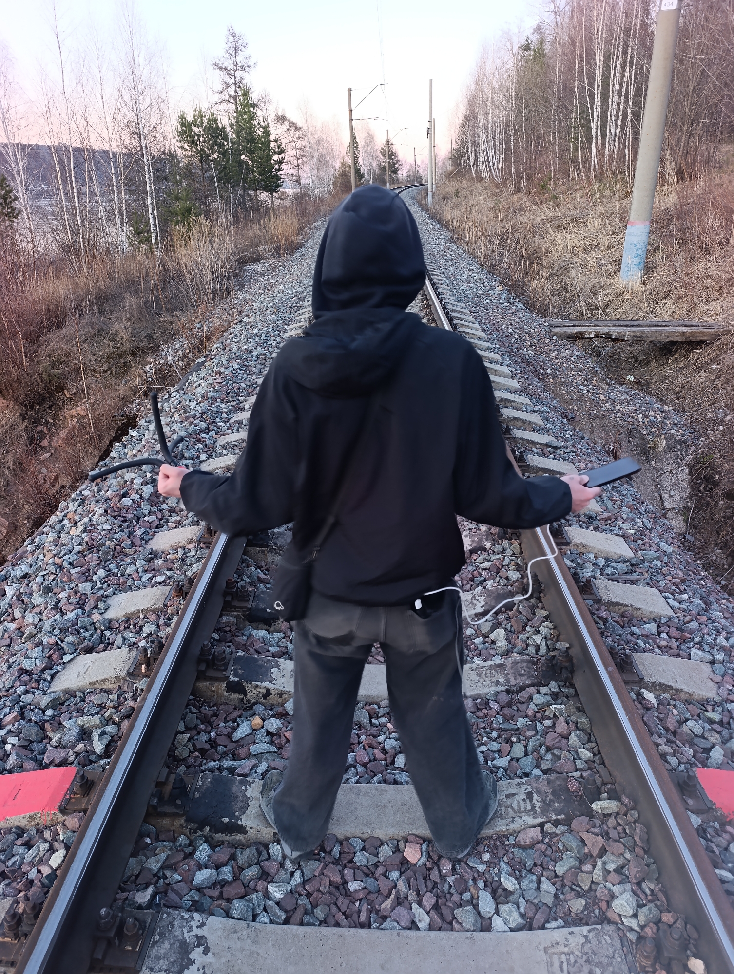 Person walks railway tracks in Krasnoyarsk during spring afternoon