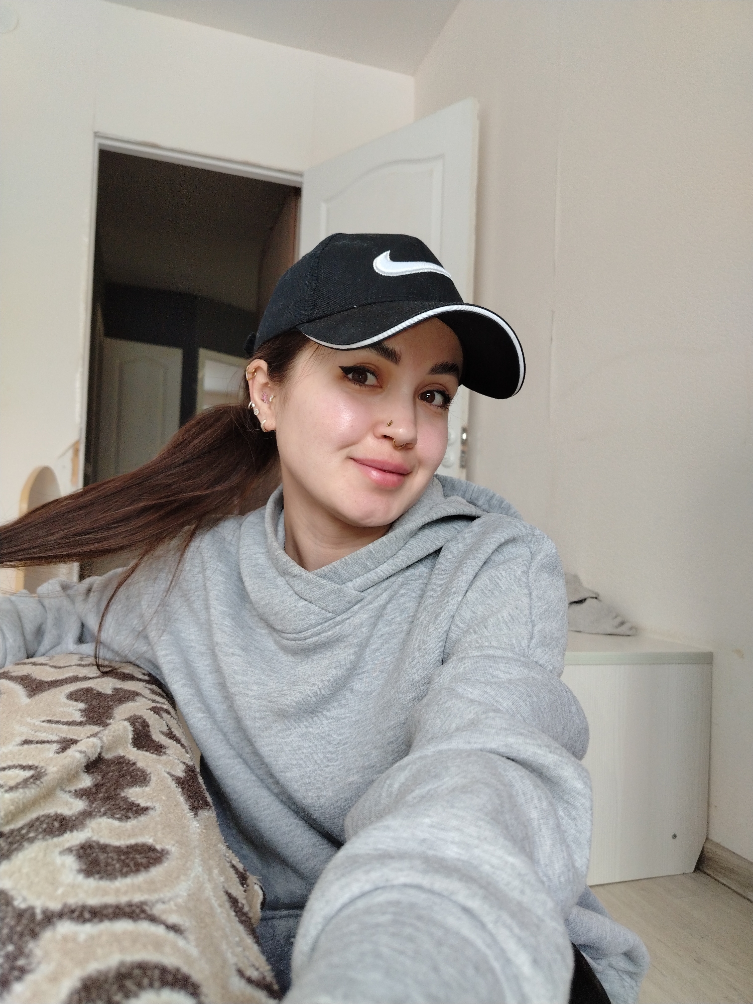 Woman takes selfie wearing Nike cap indoors