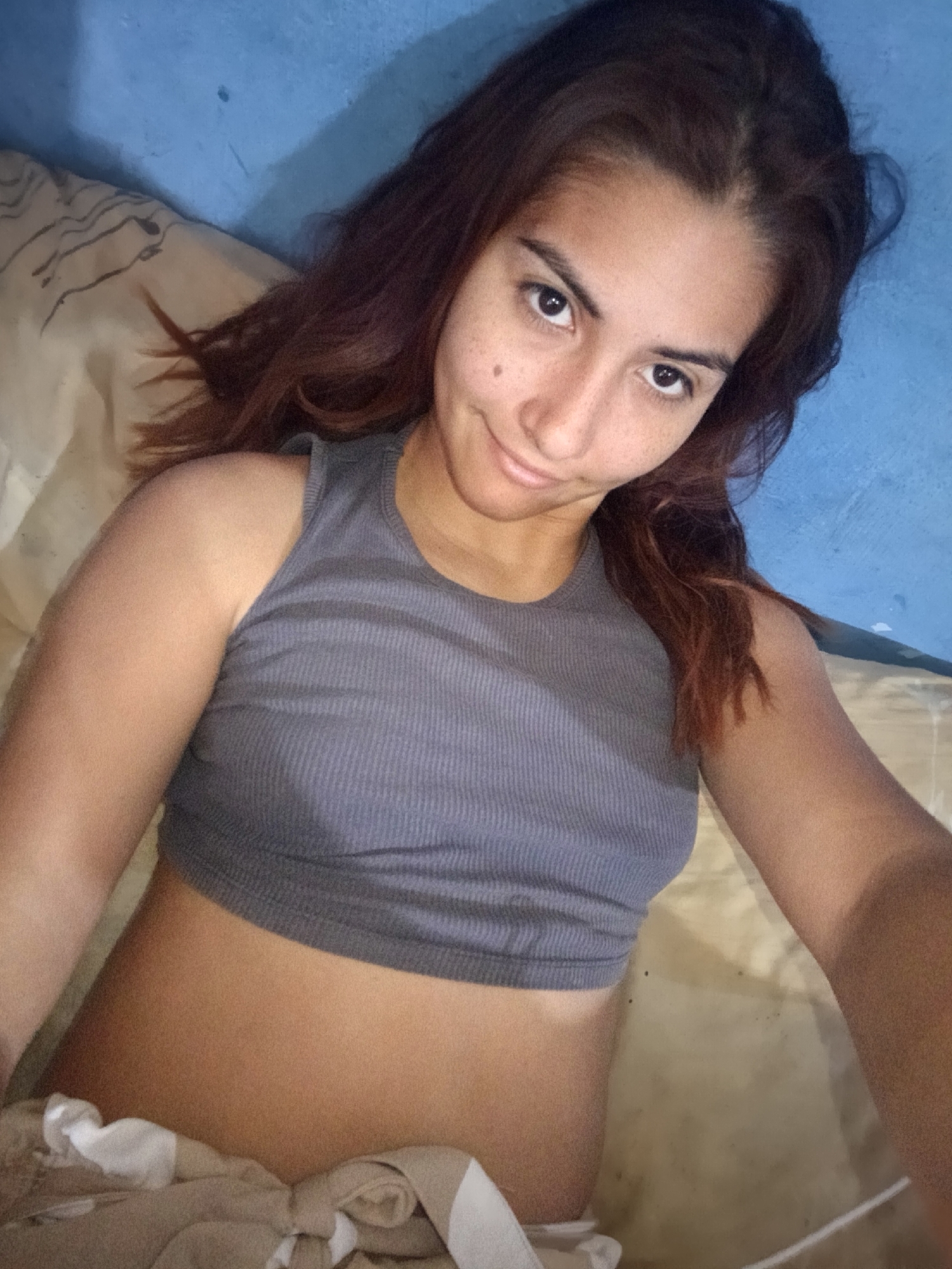 Woman documents casual afternoon with selfies in blue-walled bedroom