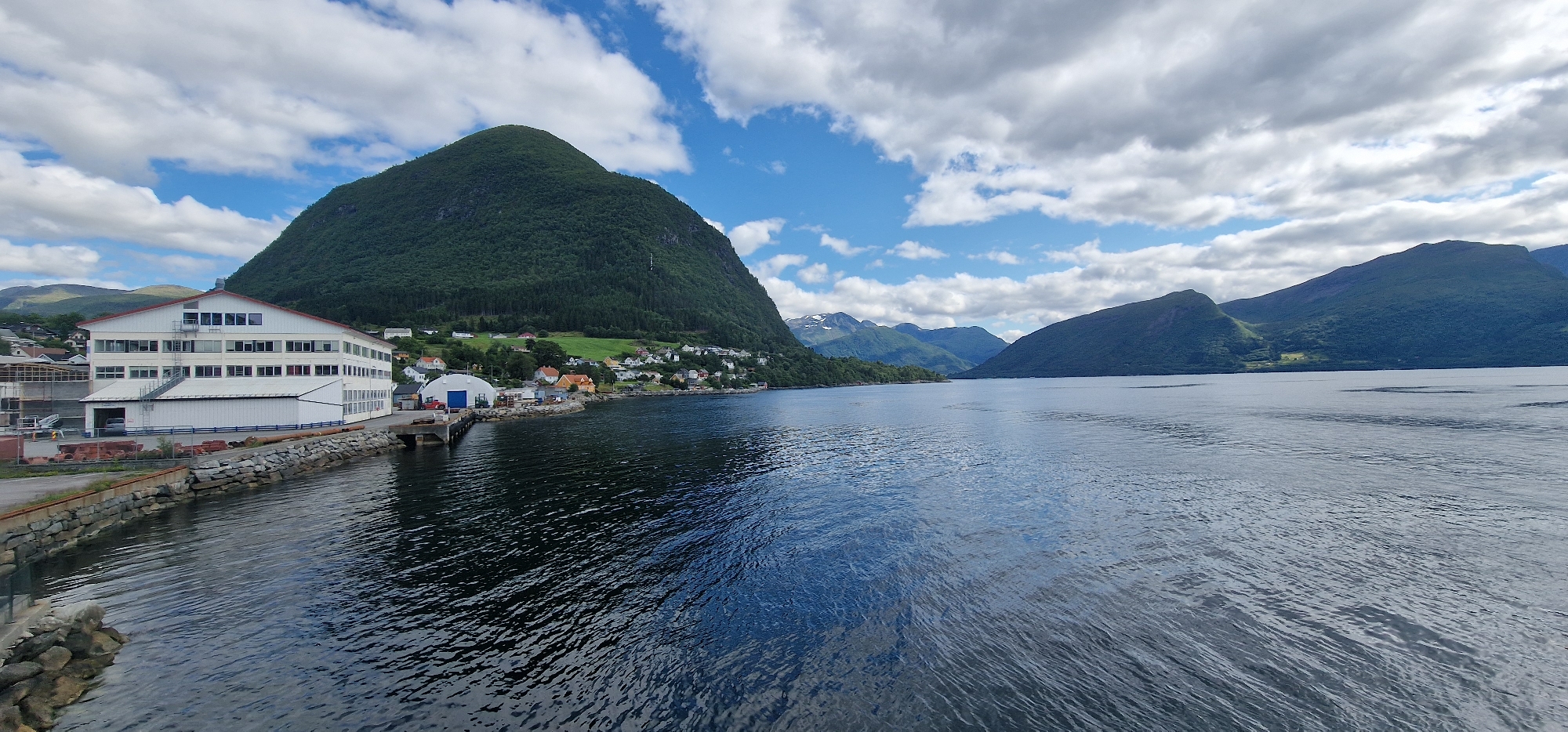 Calm fjord crossing past Volda's mountainside village
