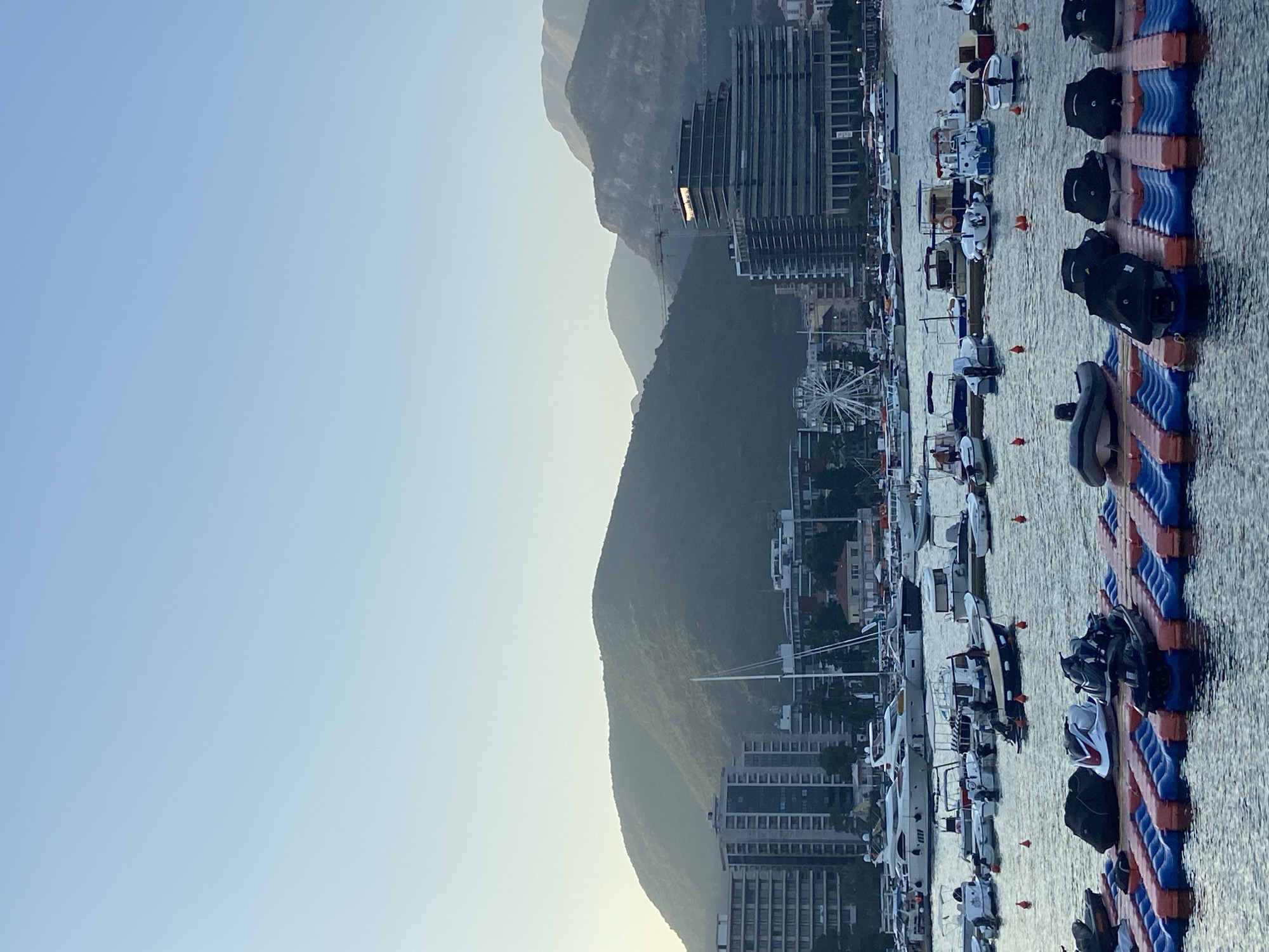 Jet skis docked at an urban harbor with mountain backdrop