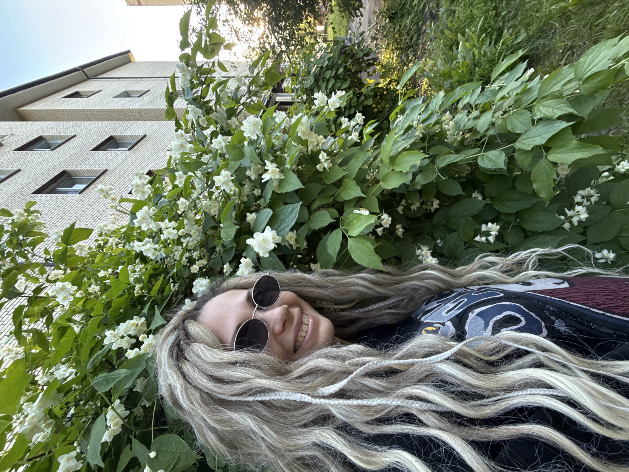 Woman poses by flowering jasmine bush in Rusanovo