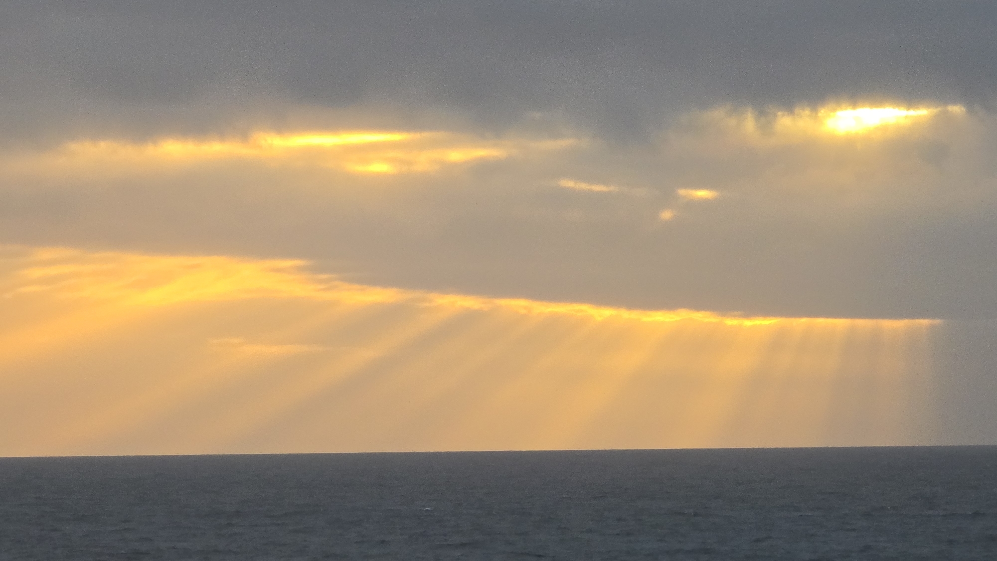 Witness captures sunset seascape through cloudy skies