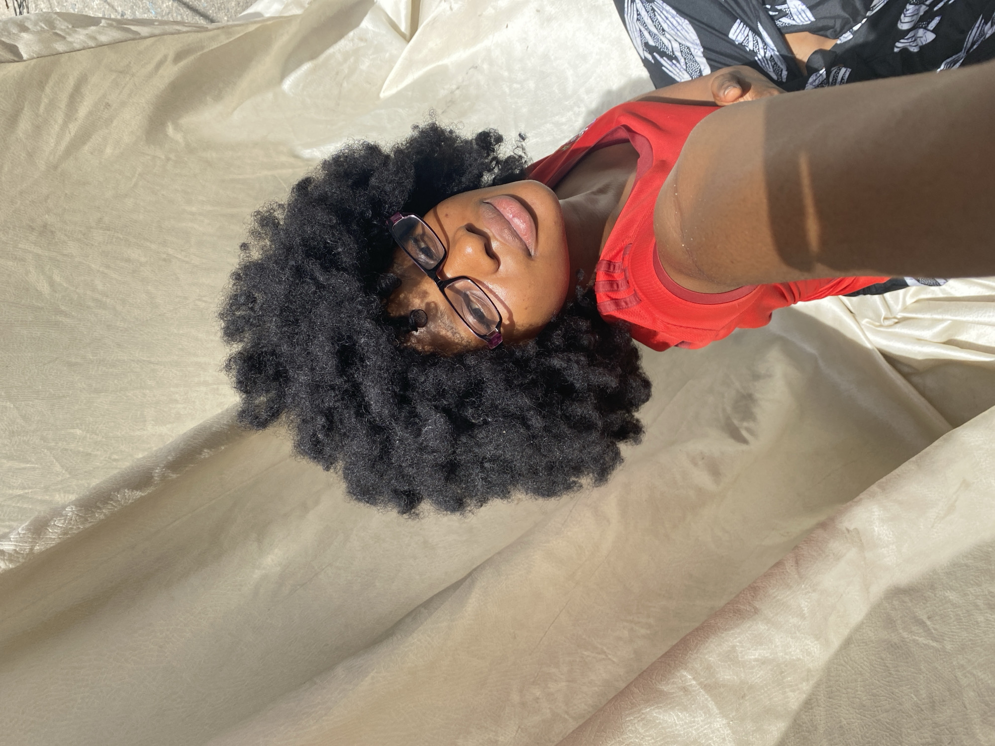 Woman in red shirt resting on fabric surface in Nigeria