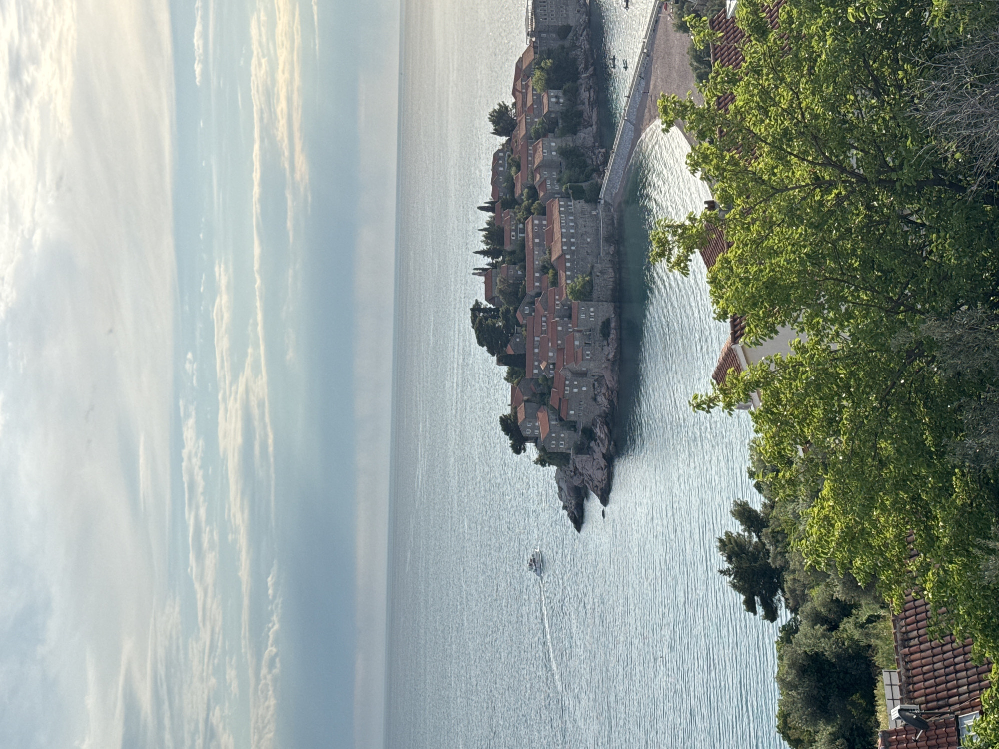 Tourists photograph scenic Sveti Stefan island resort Montenegro afternoon