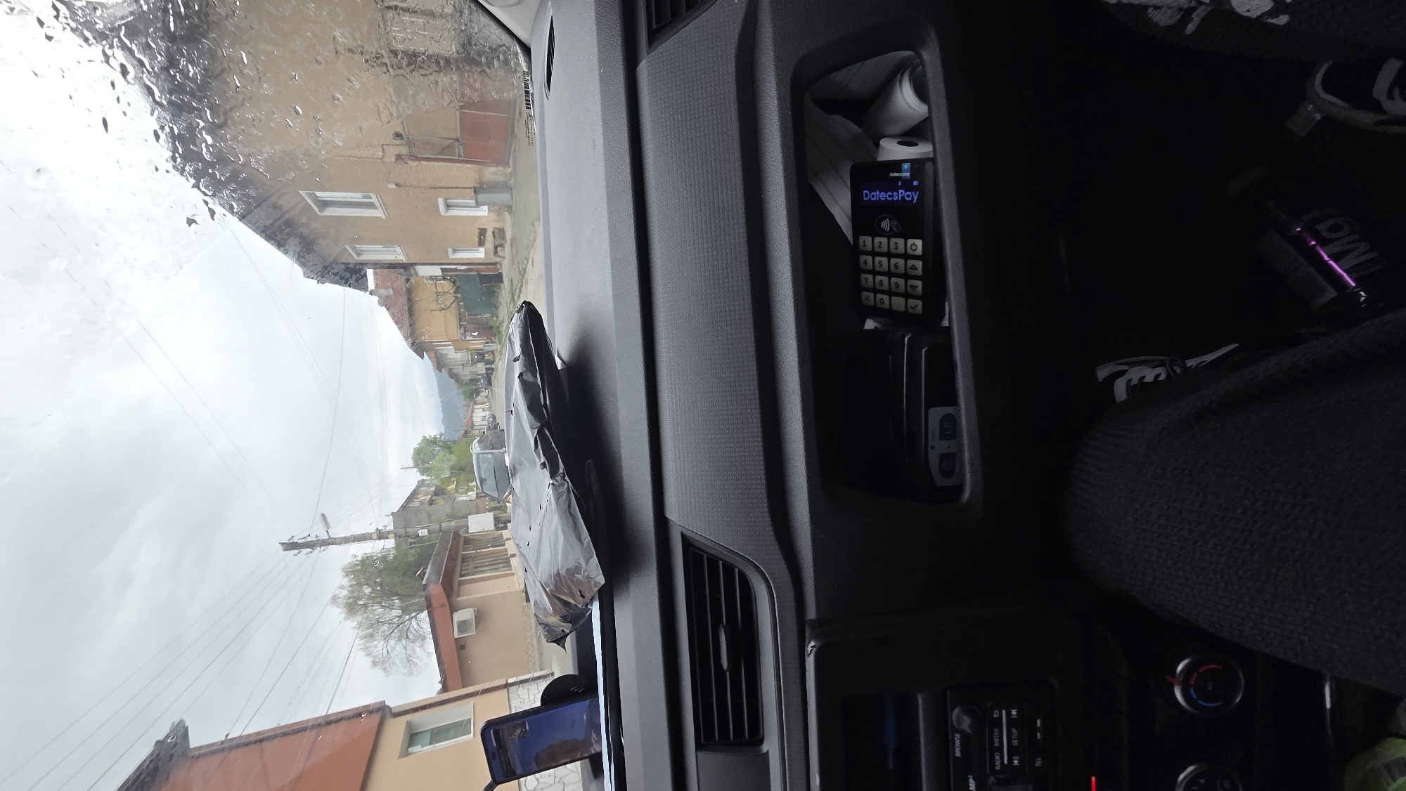 Driver documents rainy rural road journey through windshield