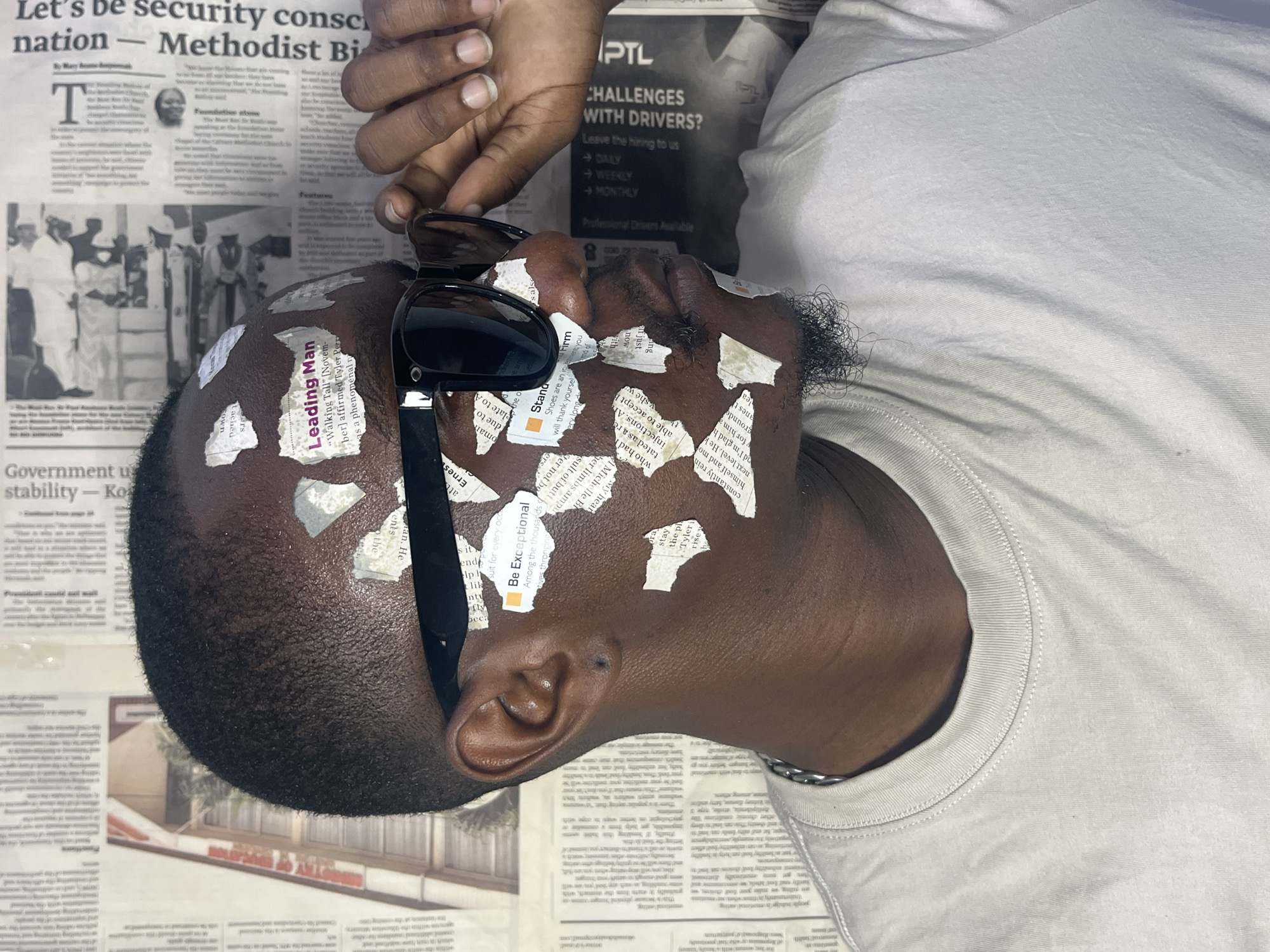 Man rests on newspaper-covered surface in Joma, Ghana