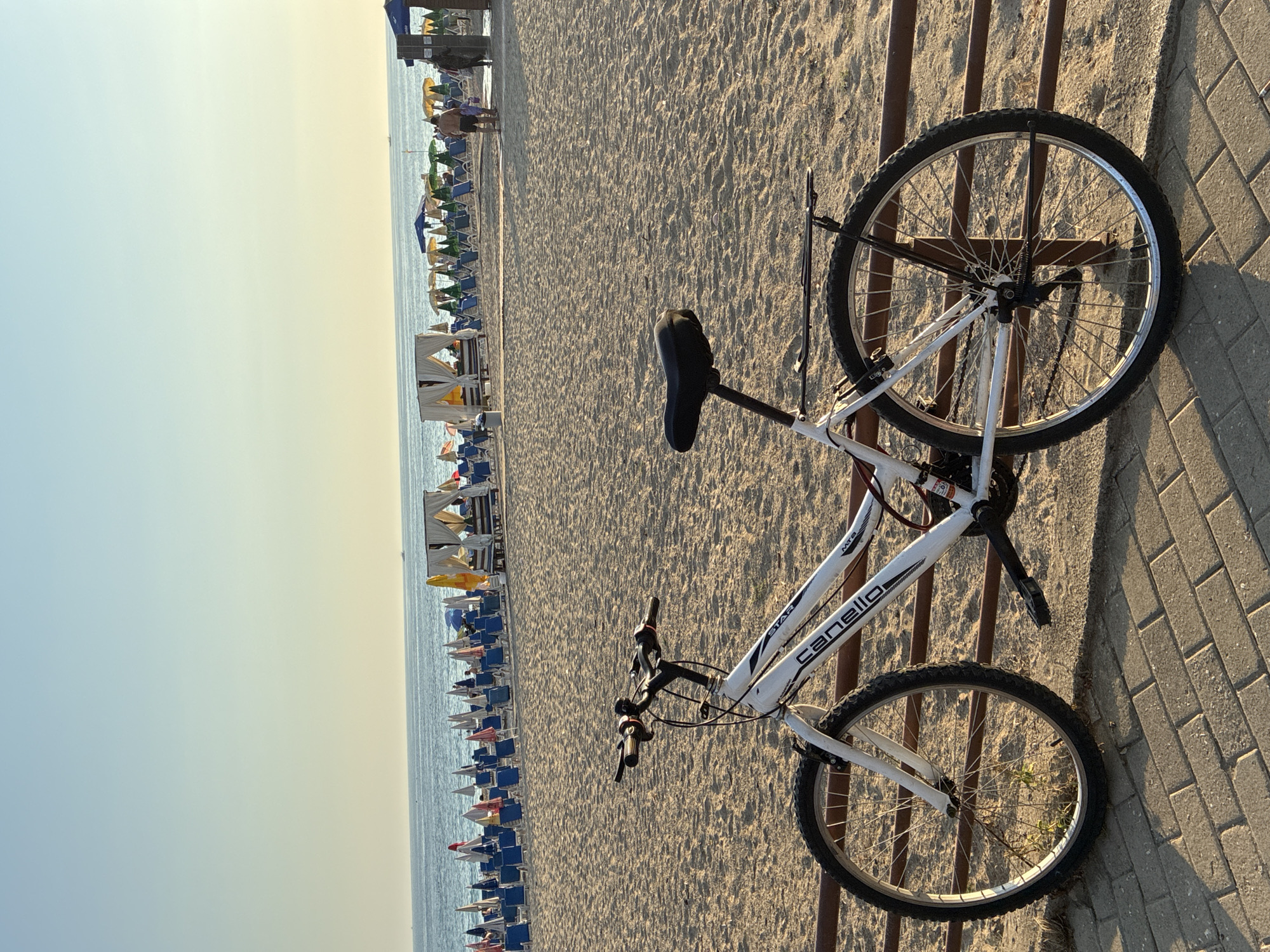 White bicycle parked along a sunny Alanya beach promenade