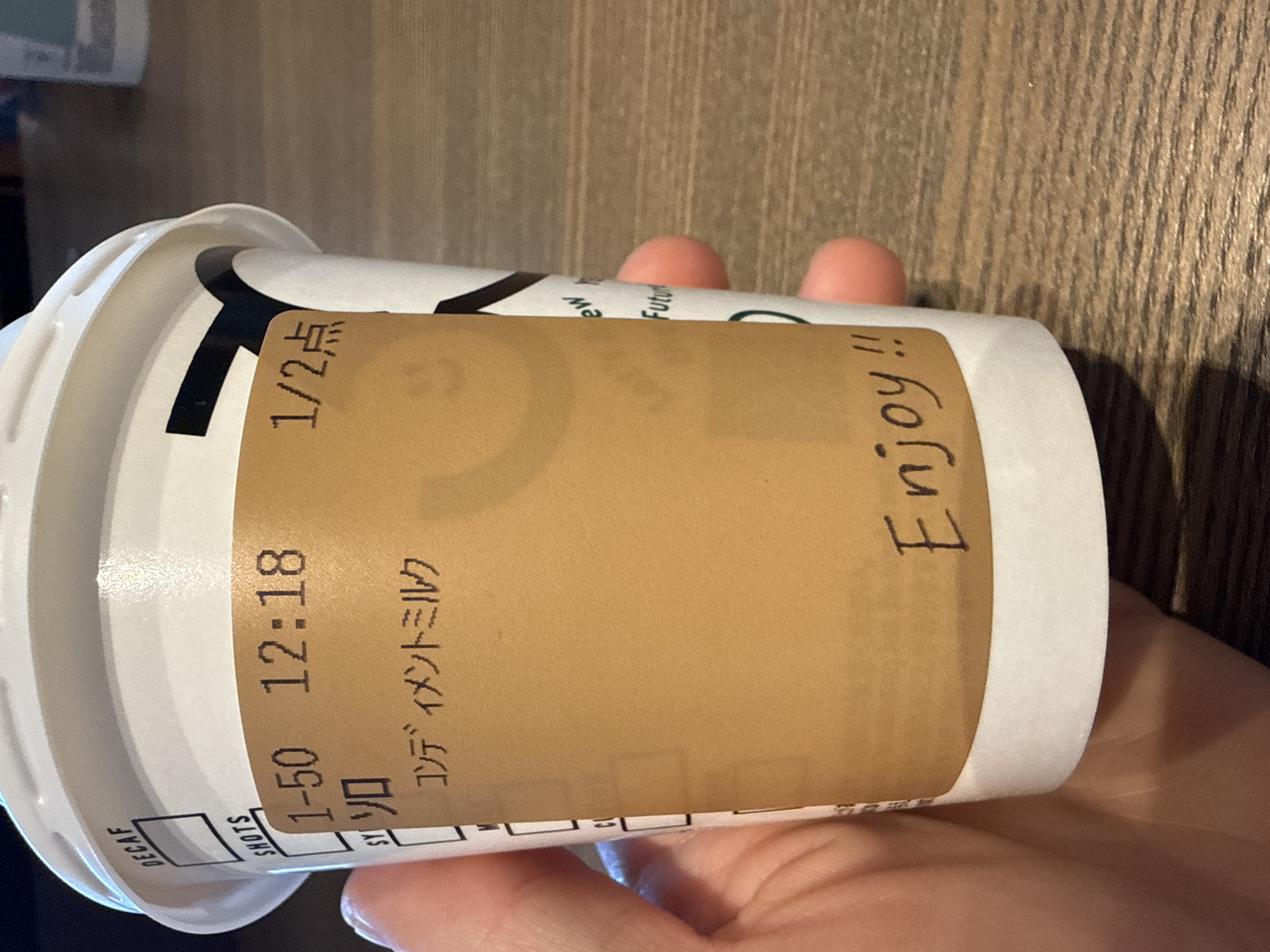 Person holds labeled Japanese coffee cup in Shibuya