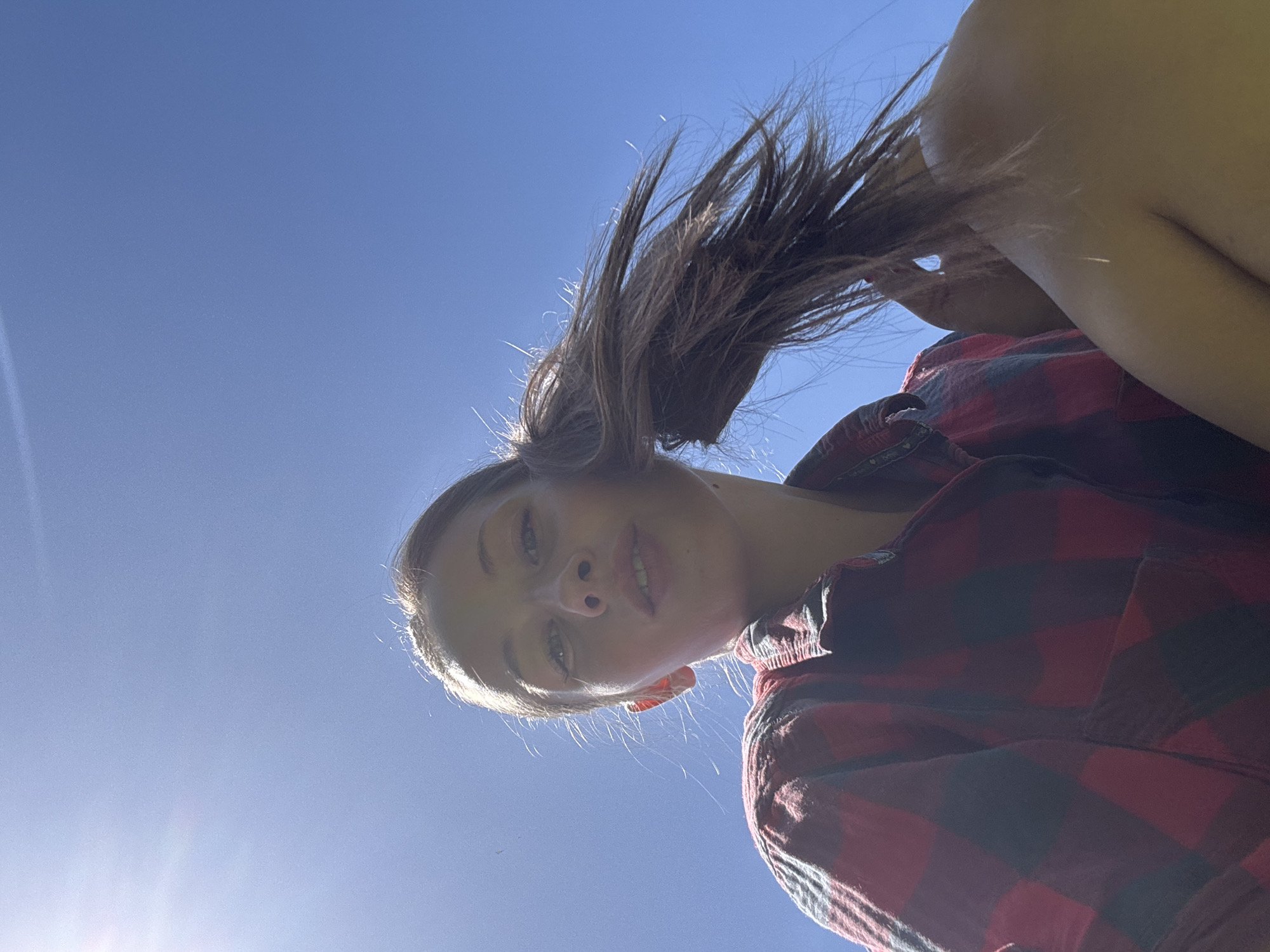 Woman in plaid shirt photographed against blue sky in Mengwi