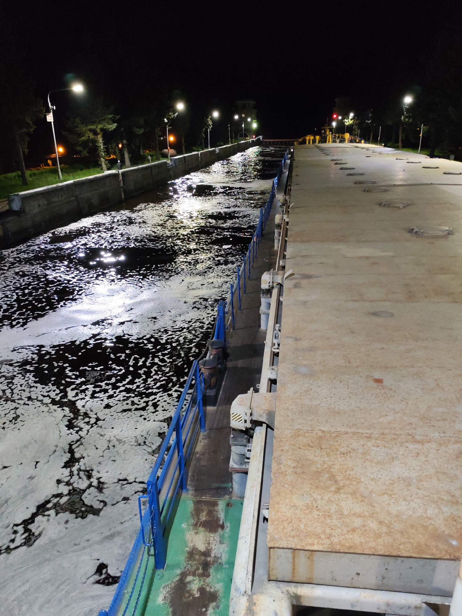 Boat transits foamy canal lock in Dubna at night