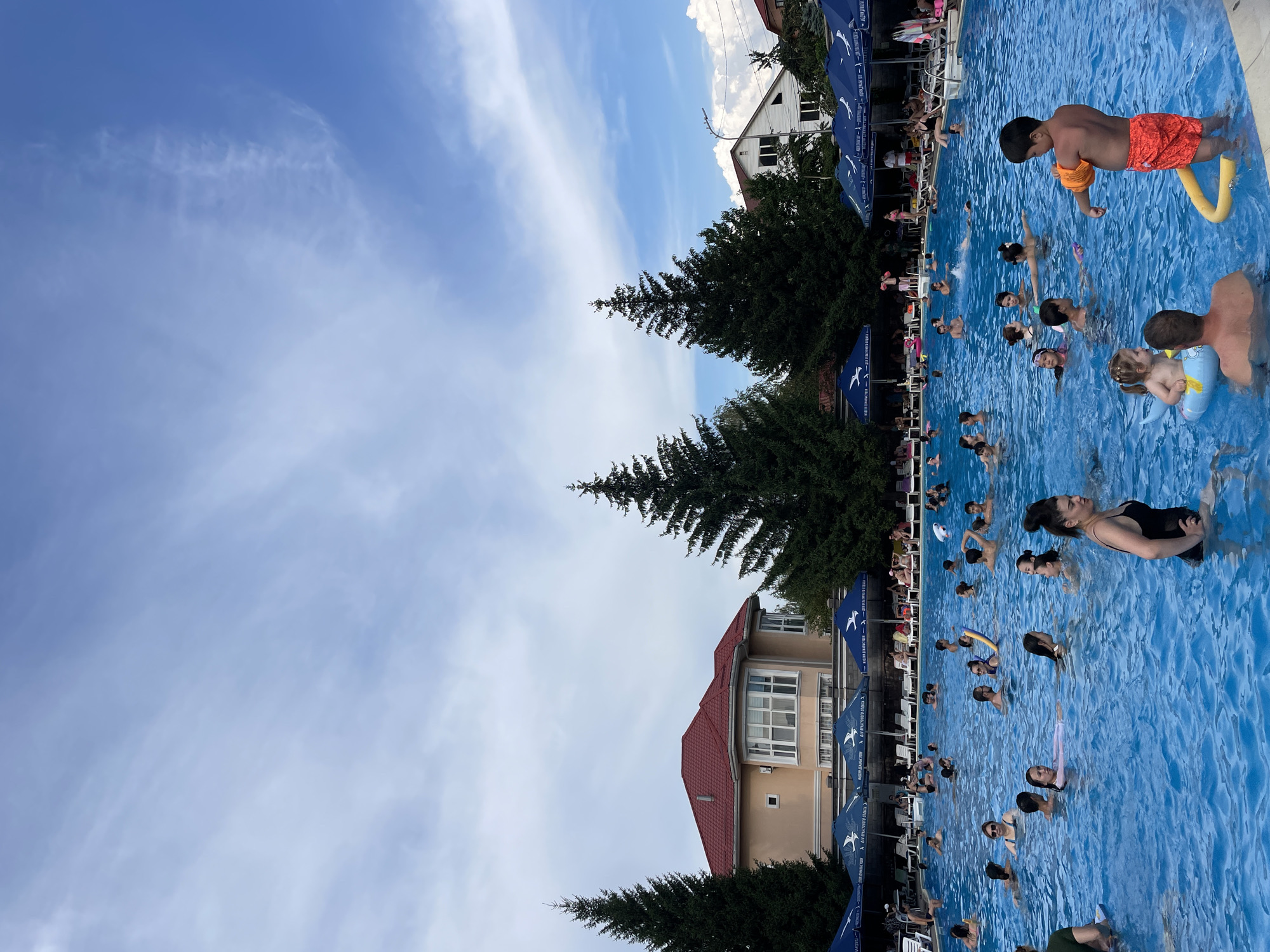 Crowded outdoor pool day at a recreational complex in Almaty