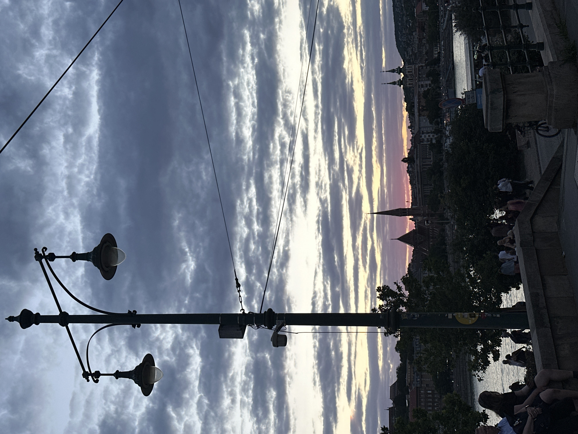 Budapest skyline at dusk, framed by an ornate waterfront lamppost