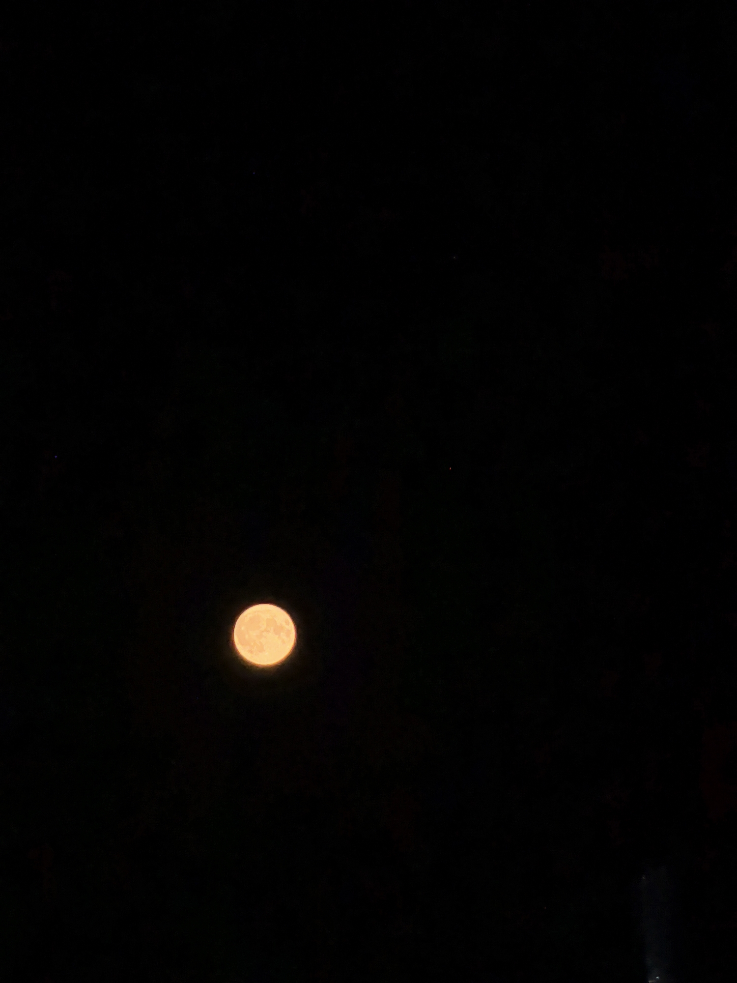 Orange moon rises over a quiet Belarusian town at night