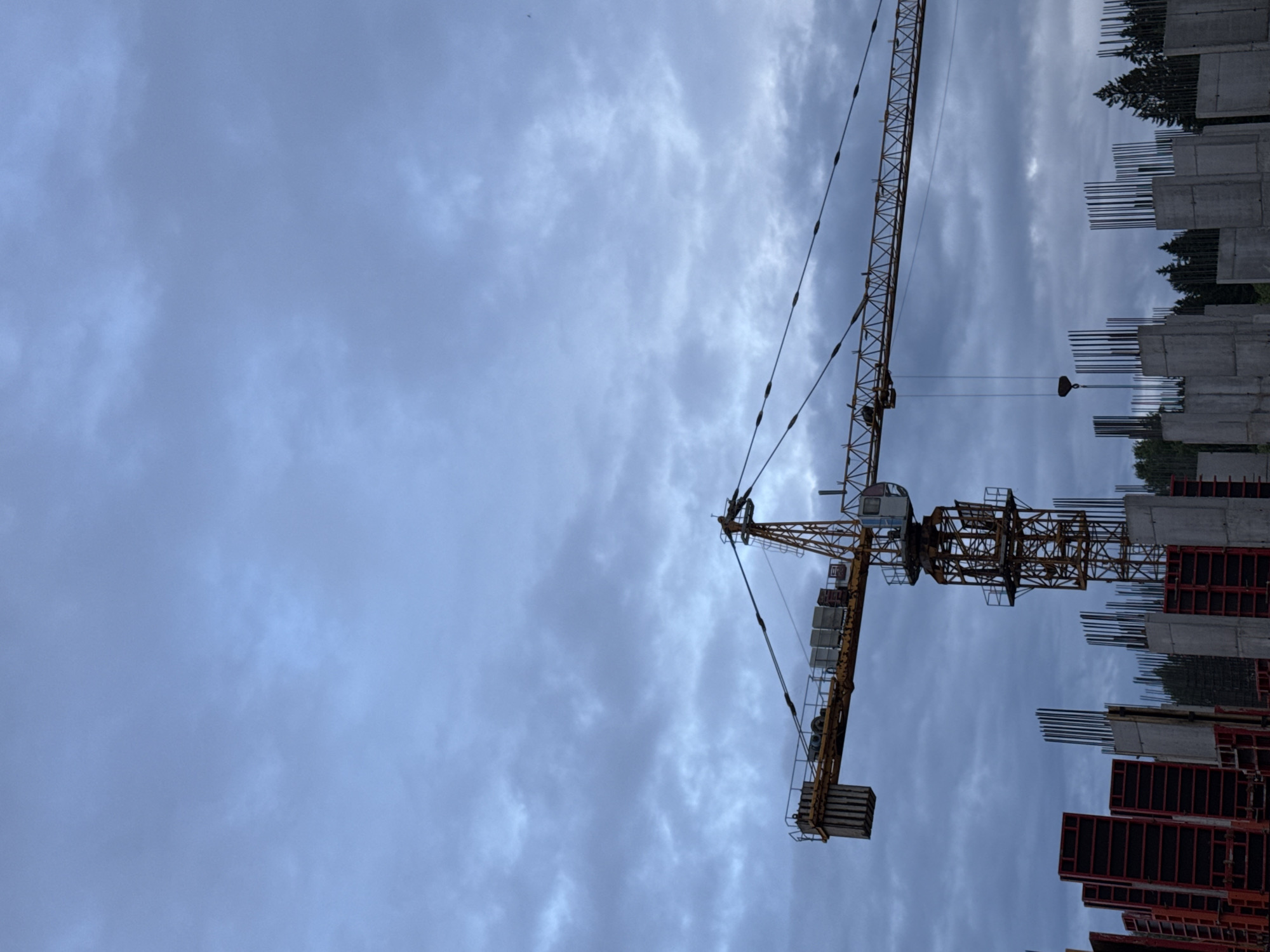 Adult carries child through Izhevsk construction site under overcast skies
