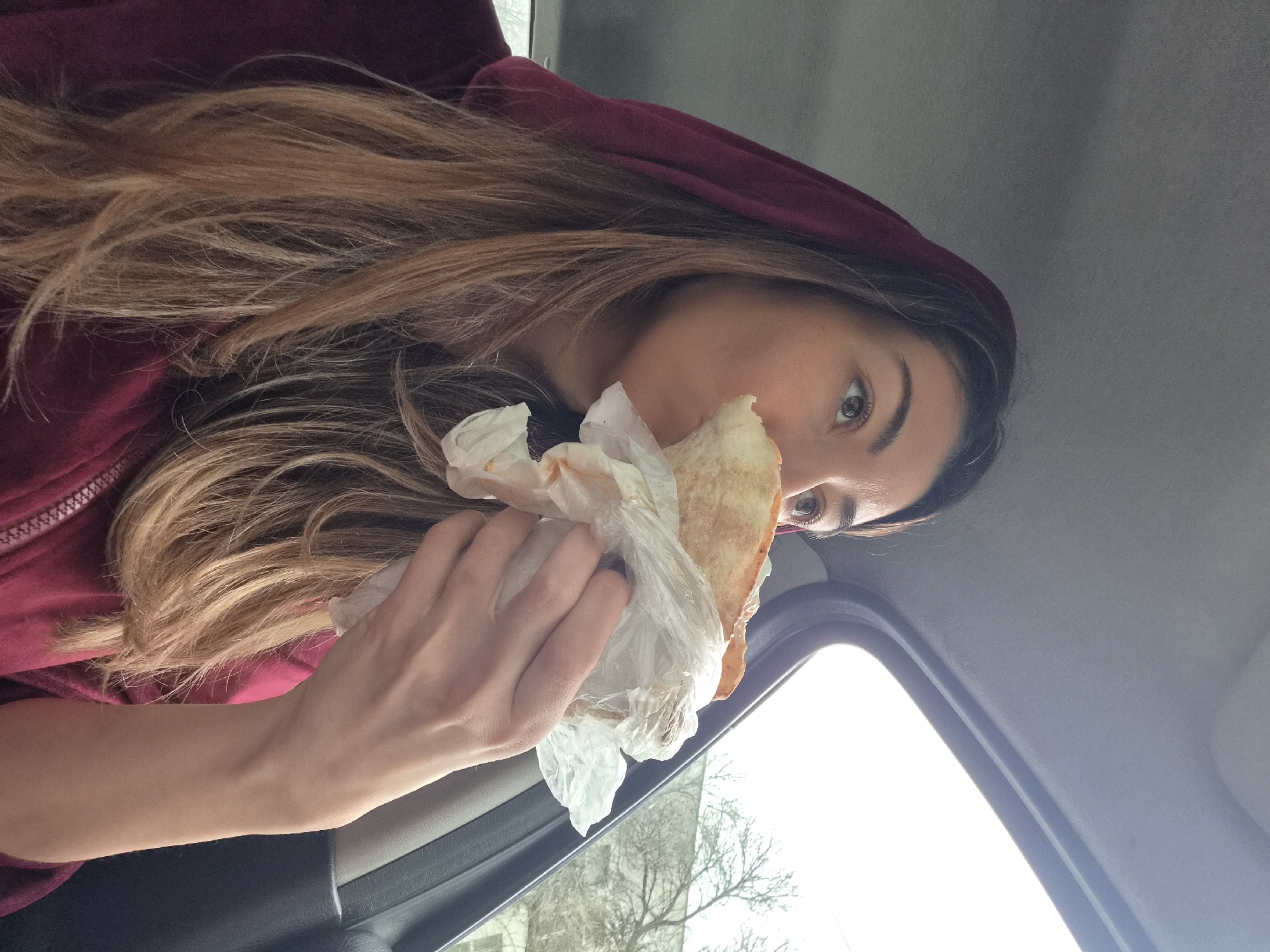Woman eats shawarma sandwich in car in Plovdiv