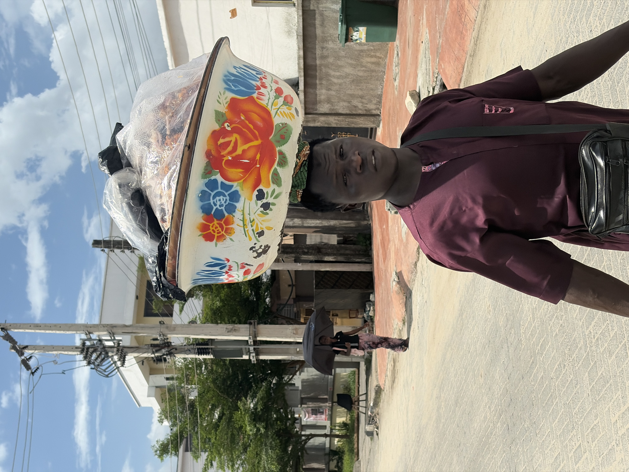 Man carries food bowl on head in Igboefon street