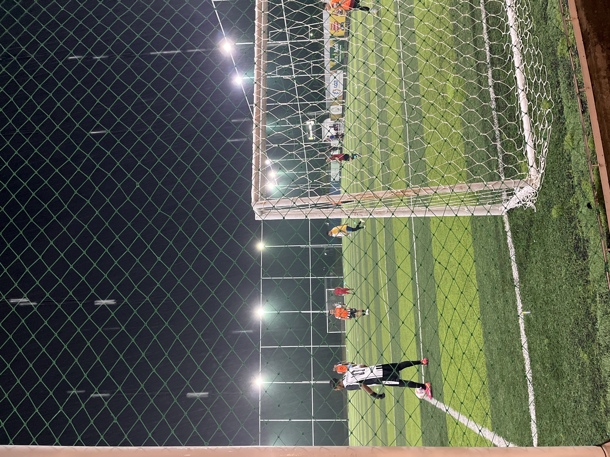 Evening soccer match and commercial activity documented in Lhokseumawe