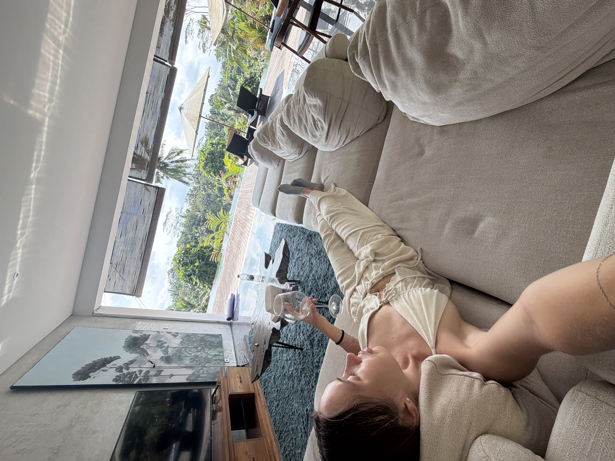 Woman relaxes with wine glass on sofa in Petulu home