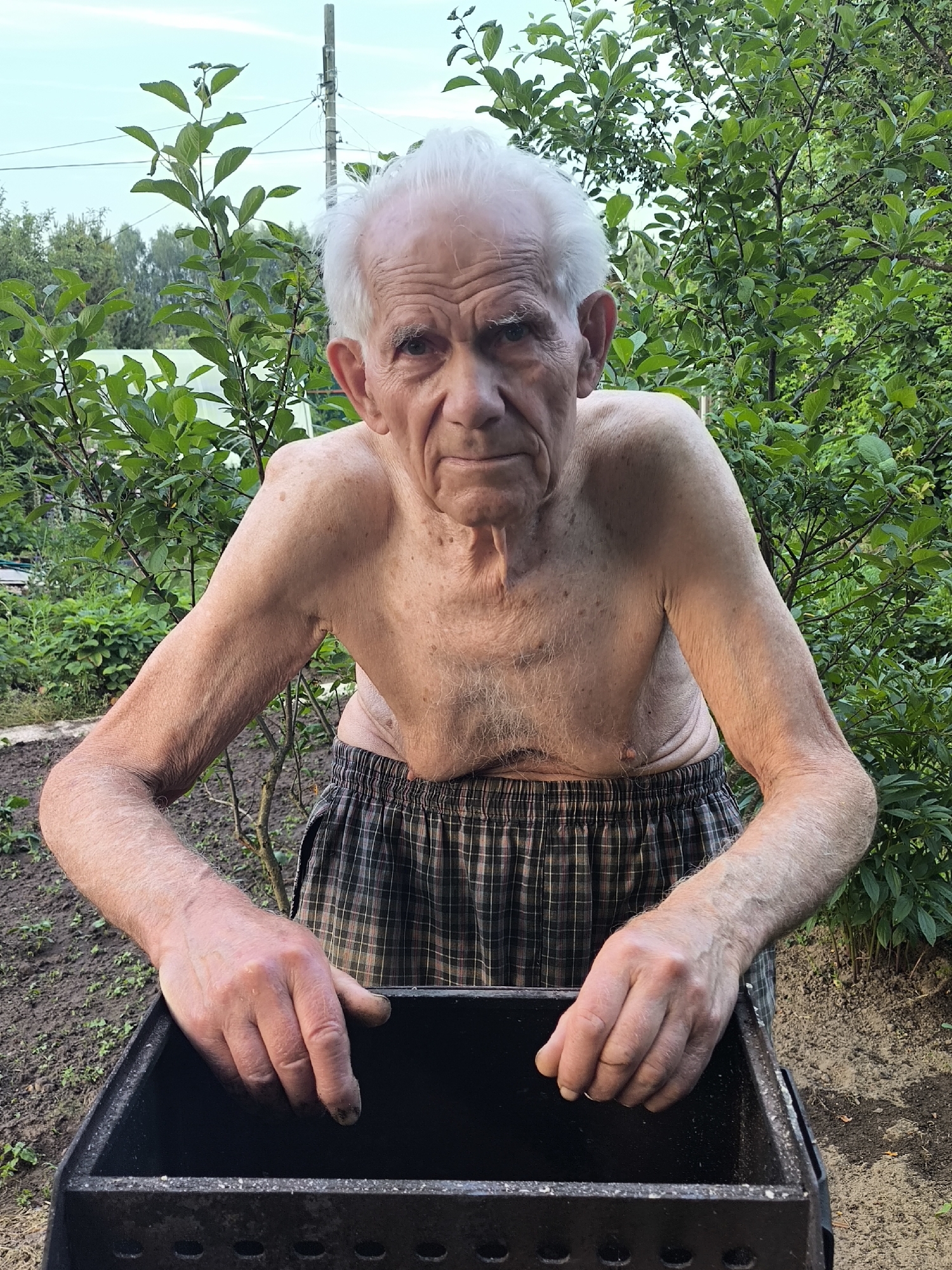 Elderly man grills in backyard during summer afternoon