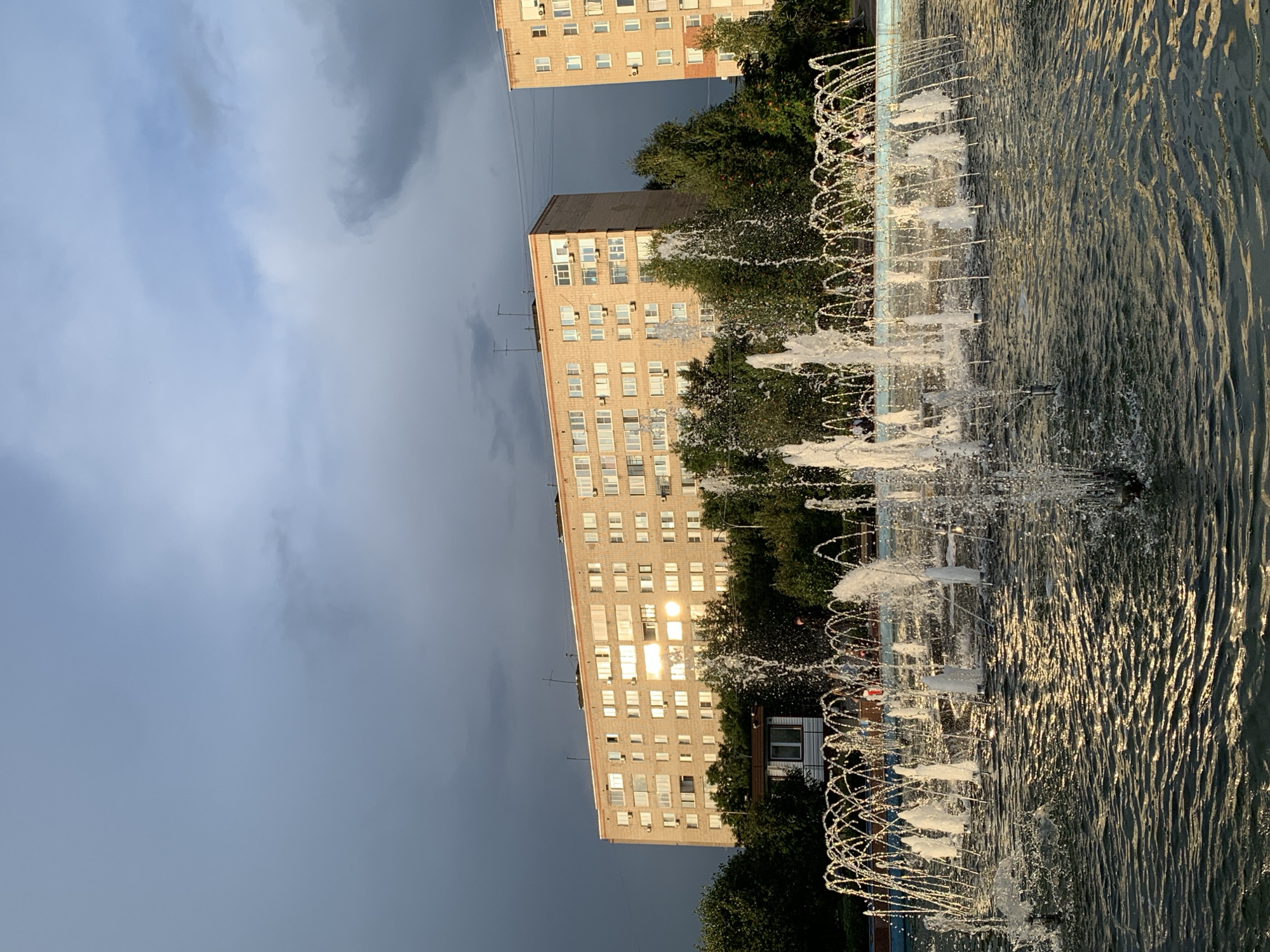 Prokopyevsk park fountain and Soviet-era apartment blocks, summer afternoon