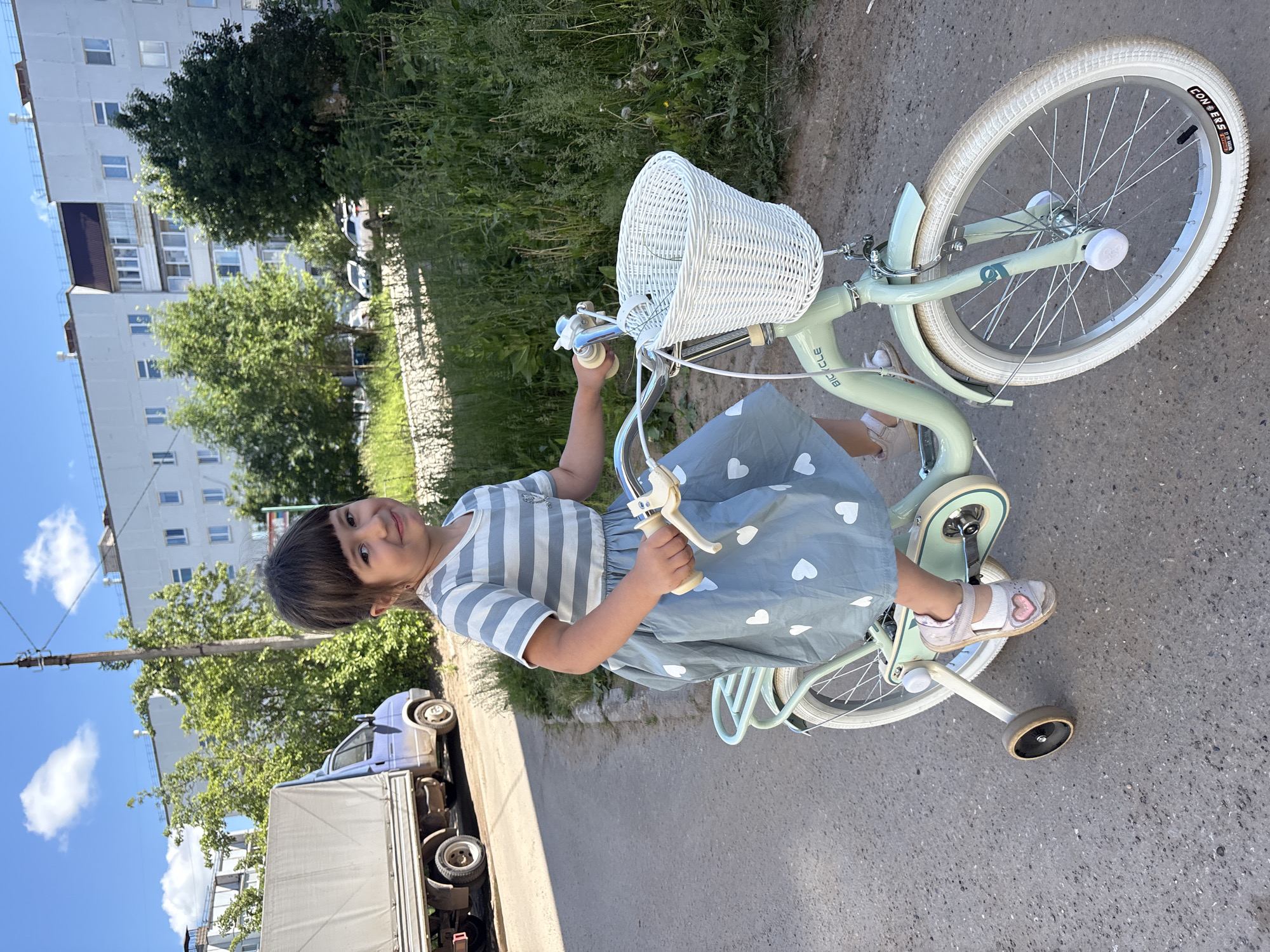 Child learns to ride bicycle with training wheels