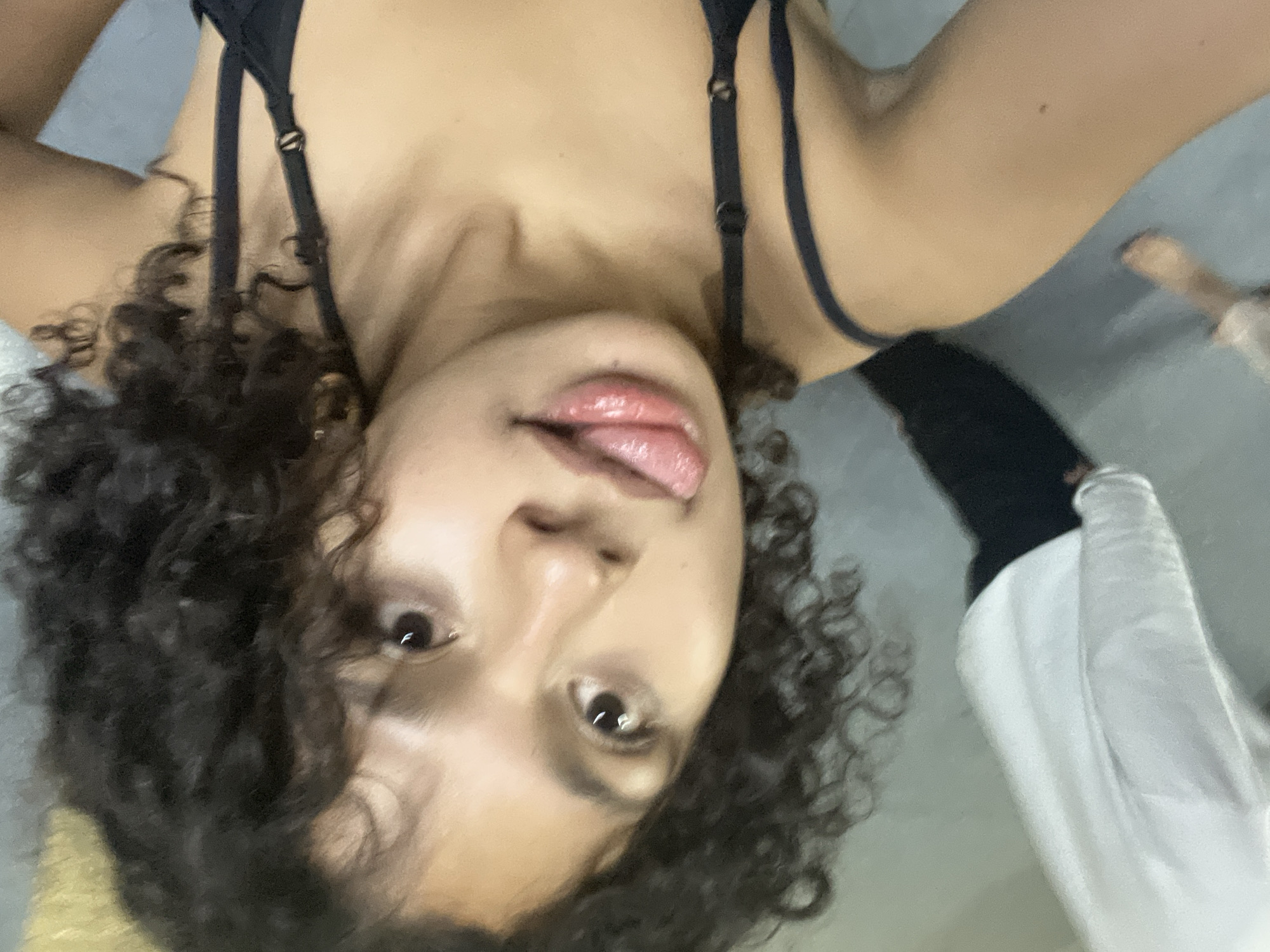 Person photographed upside down with tongue out, second individual partially visible