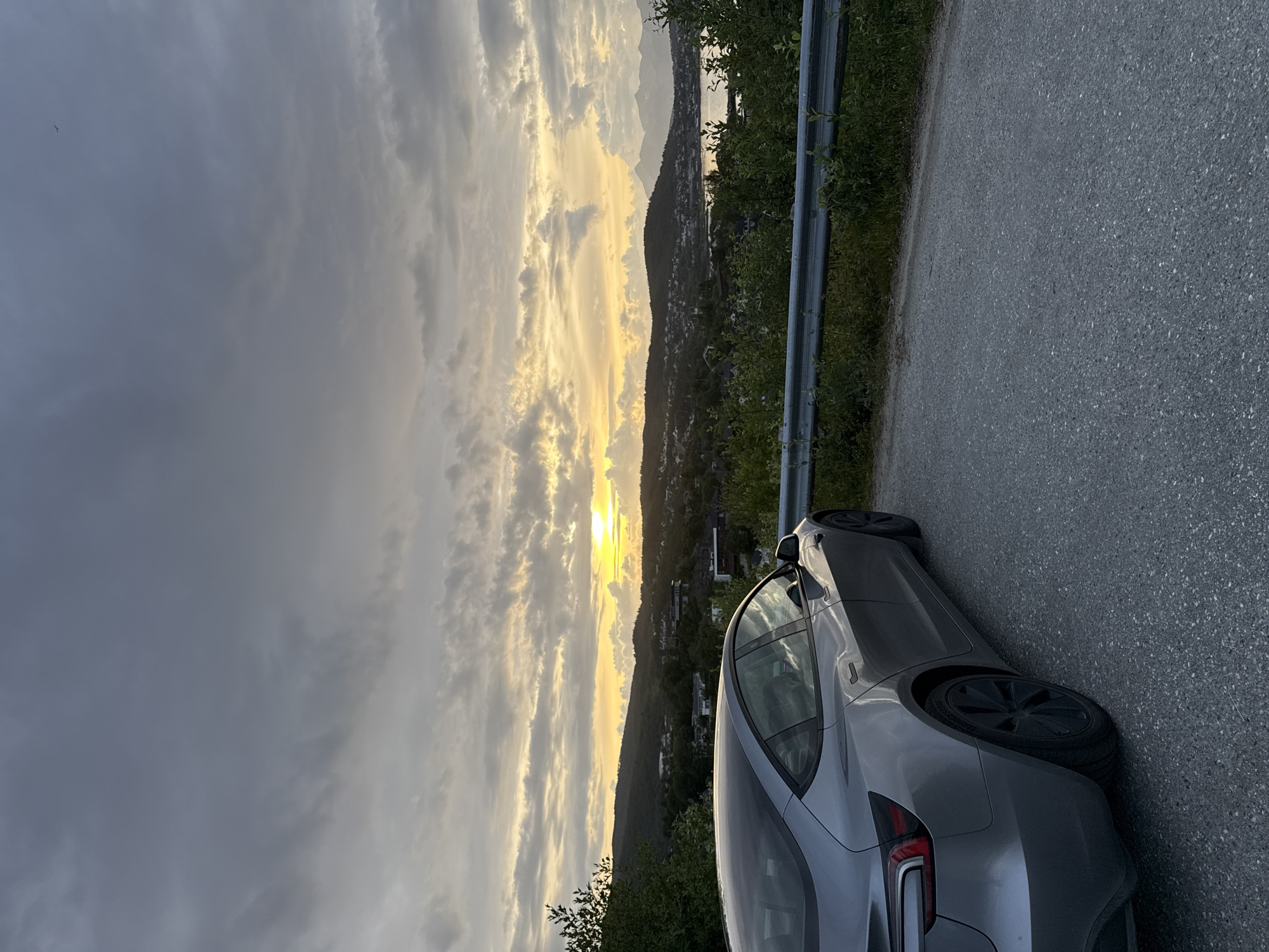 Silver EV parked at sunset overlook above Harstad fjord