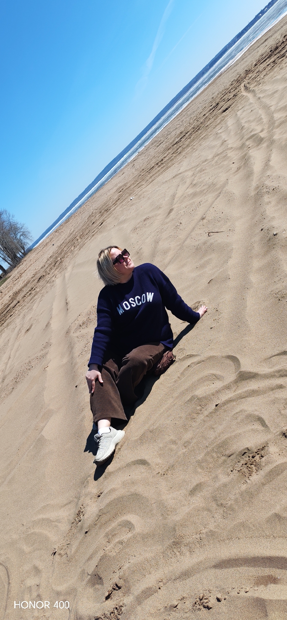 Woman in Moscow sweatshirt visits sandy beach in Noviy, Russia
