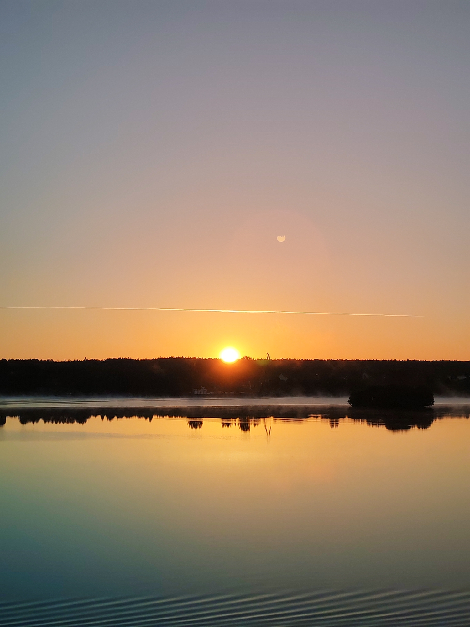 Sunrise breaks over a still lake near Devyatiny, Russia